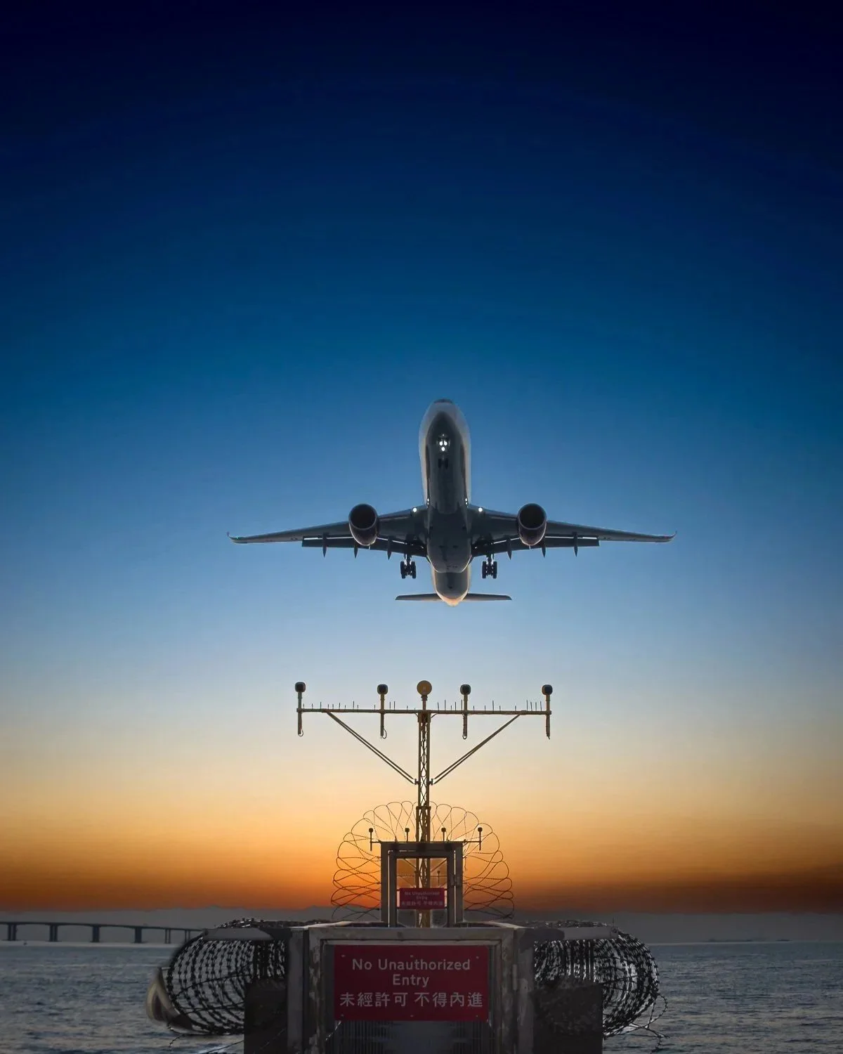Fine art print titled Airborne featuring a symmetrical passenger jet landing over airport lights at sunset.