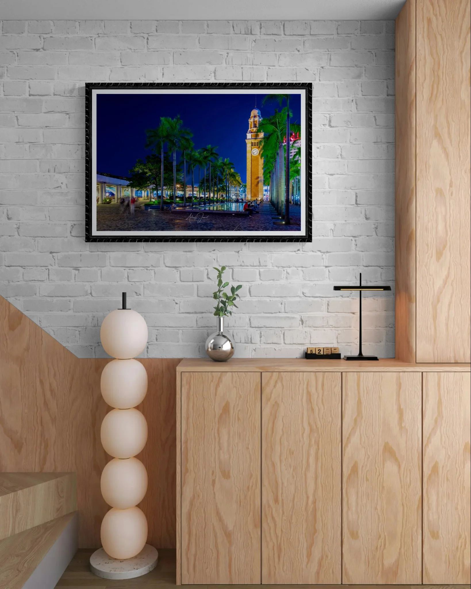 Framed Hong Kong Clock Tower print hanging on a modern wall above a wooden cabinet in a styled interior.