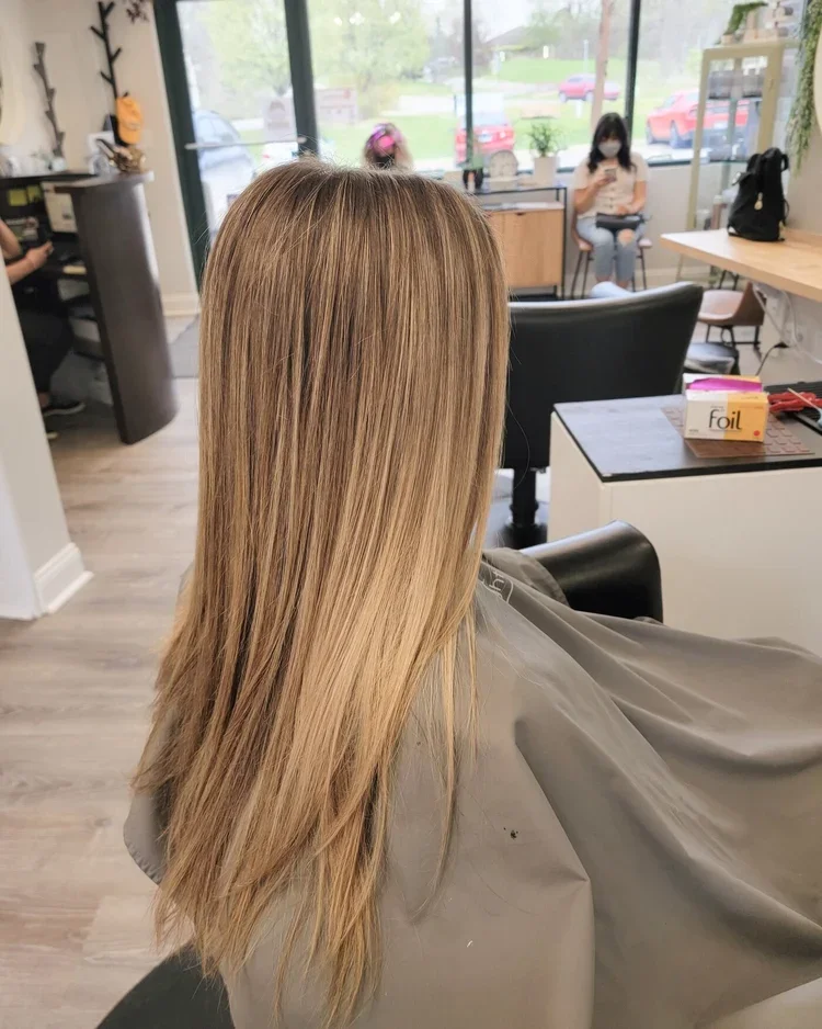 A woman with freshly styled, long, blonde hair sitting in a salon chair.