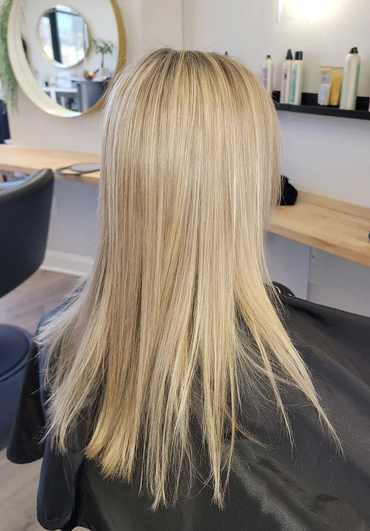 Blonde woman with freshly styled hair sitting in a salon chair