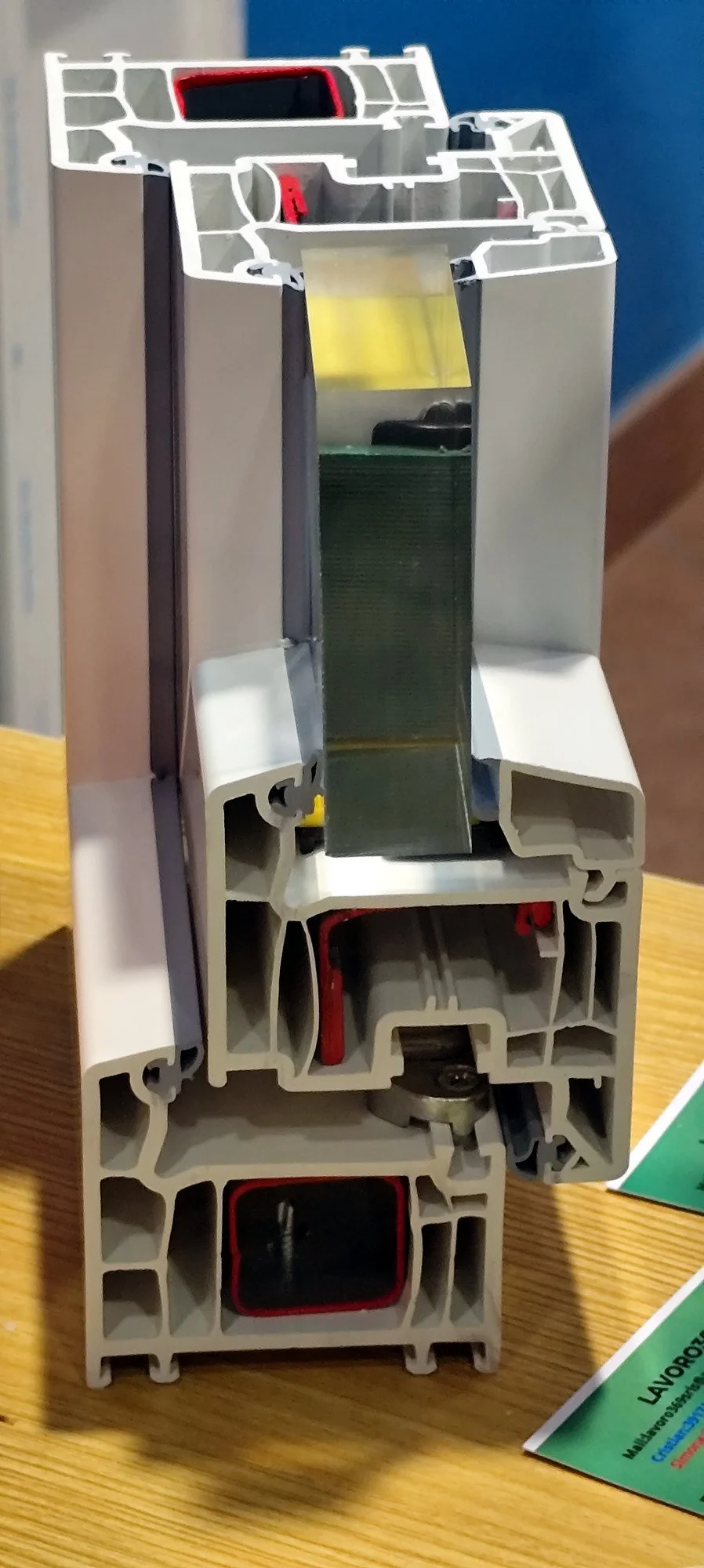 Sezione di una finestra o porta in PVC tagliata verticalmente, mostrando l’interno della struttura con vari spazi e componenti.