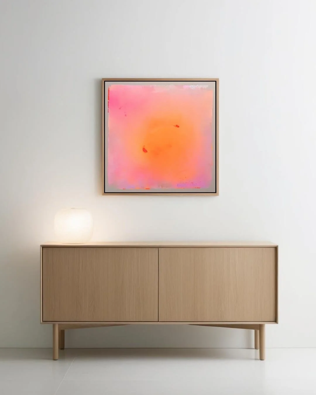 Modern room styled with a abstract sun painting featuring pink, orange, and purple tones with subtle glitter mounted on a neutral wall