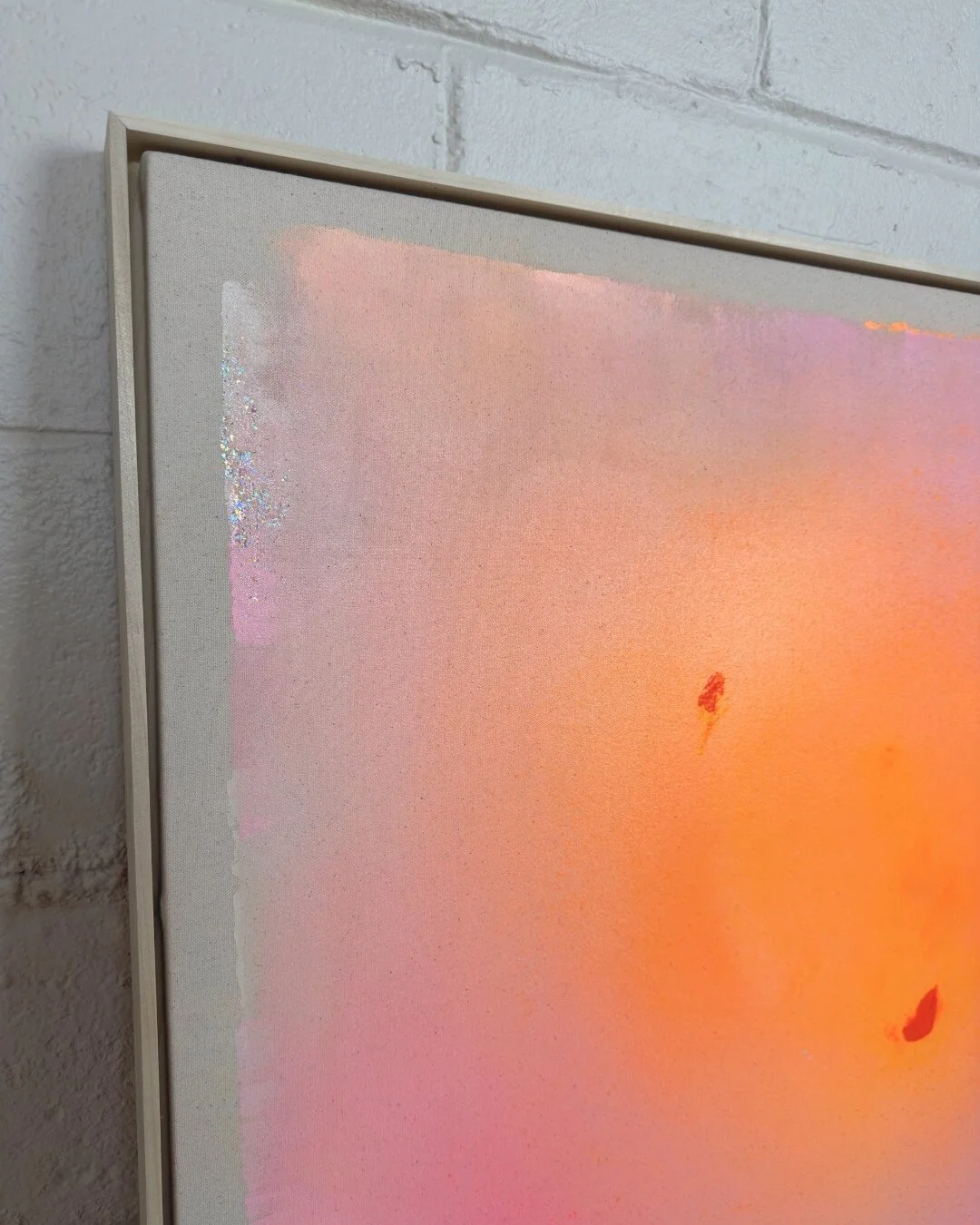 Detail shot showing delicate sparkle, purple accents, and soft canvas texture in a pink and orange gradient painting