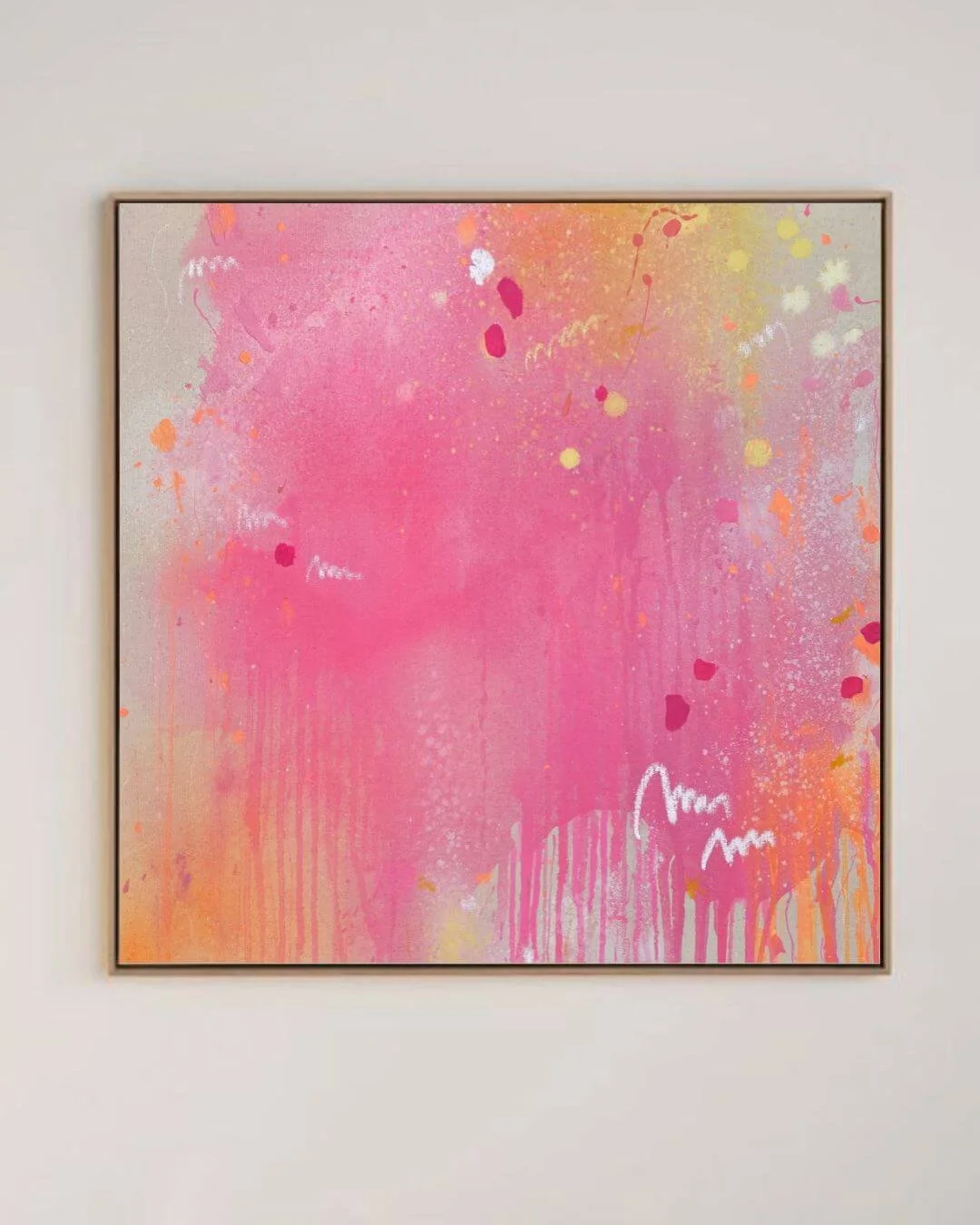 Frontal view of a vibrant square abstract painting featuring bold hot pink, orange, and yellow spray effects with white scribble marks by Vanessa Ochi