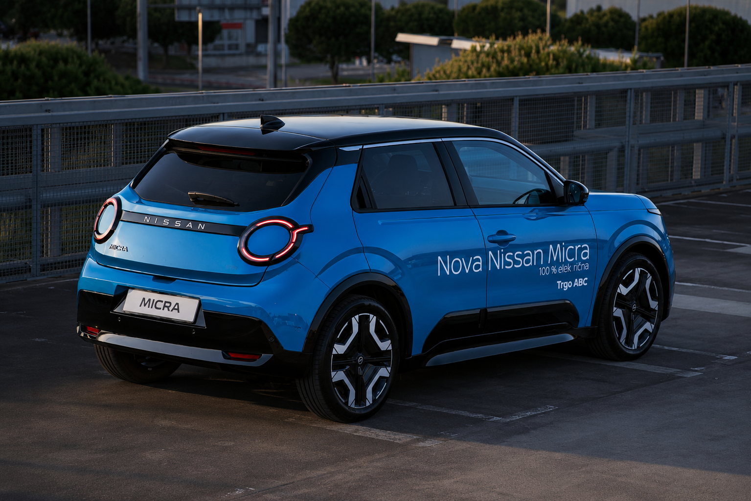 Blue Nissan Micra electric car parked in a lot, with promotional text on the side promoting the Nova Nissan Micra, 100% electric
