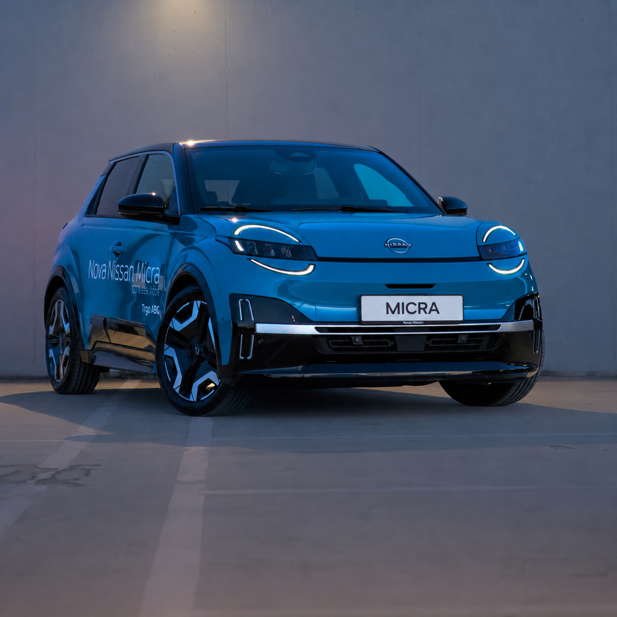 Blue Nissan Micra electric car parked in a dimly lit area, showcasing modern design with LED headlights and a unique wheel design.