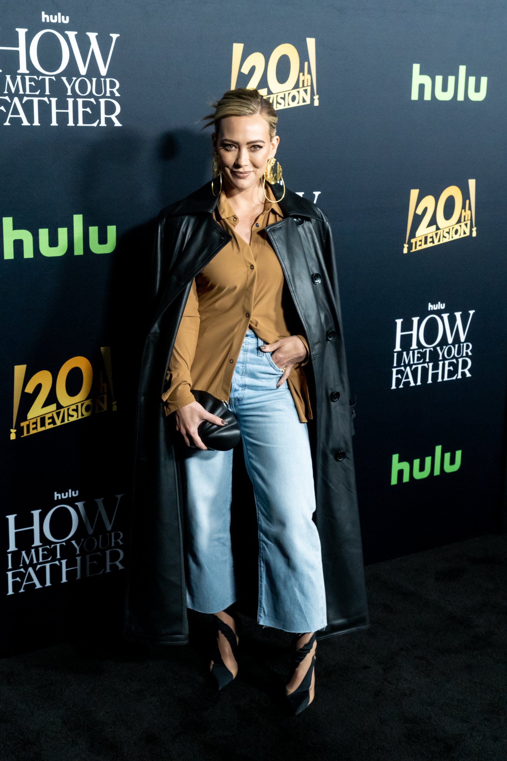 Hillary Duff standing in front of a black backdrop with logos and text for Hulu and the 120th Television event for How I Met Your Father TV show.