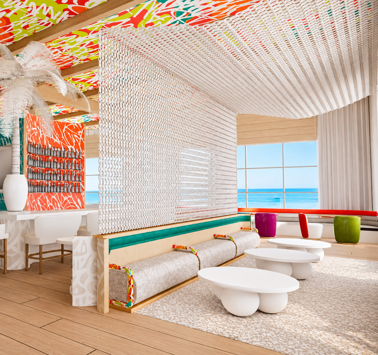 Bright, colorful interior with large windows overlooking the ocean, featuring modern white tables and a seating area with vibrant cushions, artful wall decor, a white decorative room divider, and a large potted plant.
