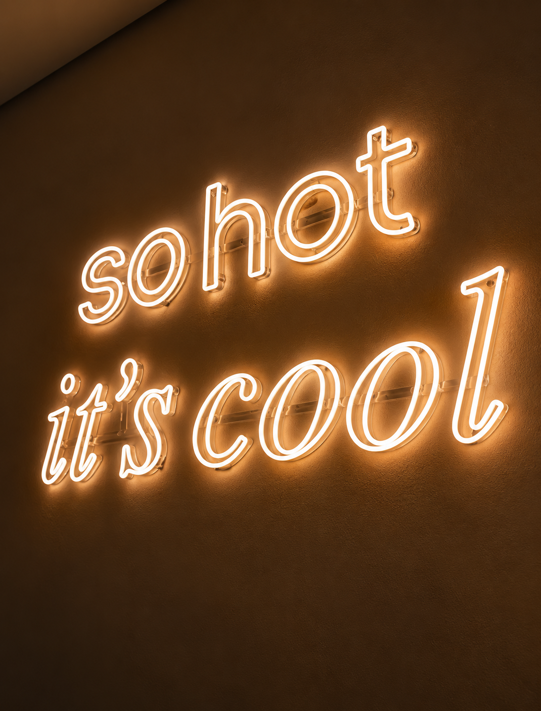 Neon sign on a wall that reads 'so hot it's cool'.