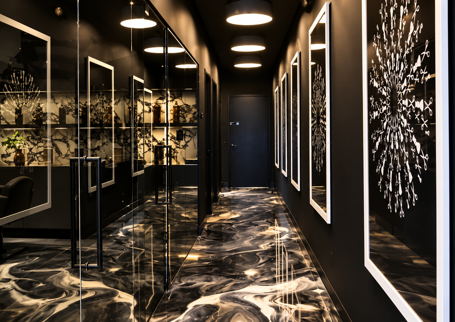 A sleek, modern hallway with black walls and a marbled black and white floor. The hallway is decorated with framed black and white artwork on the right wall and has glass doors on the left reflecting the decor. Ceiling lights are round and emit a sof