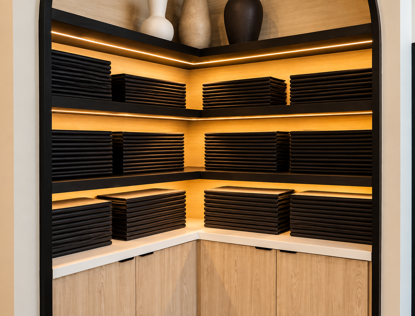 Shelves filled with black trays and decorative vases on top, illuminated by warm lighting.