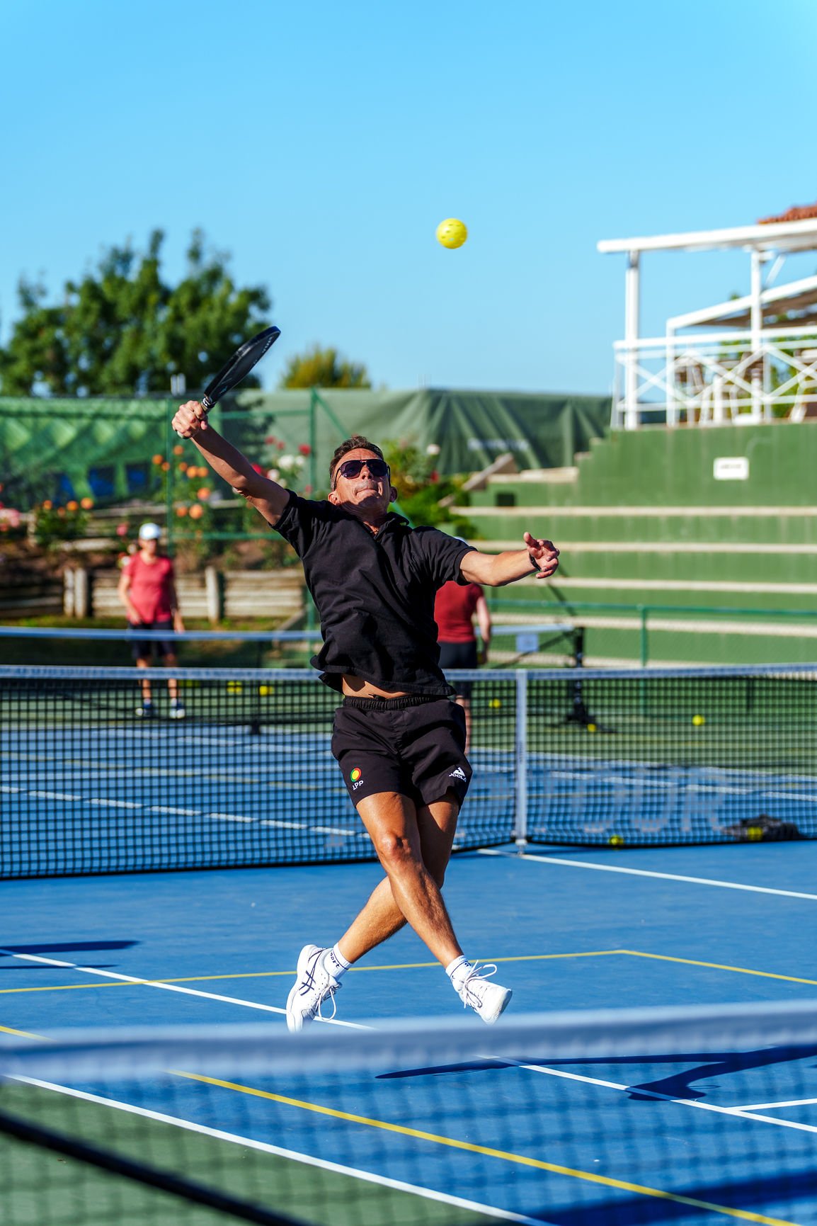 Lisbon pickleball tournament game with a player jumping and hitting a pickleball on the pickleball court