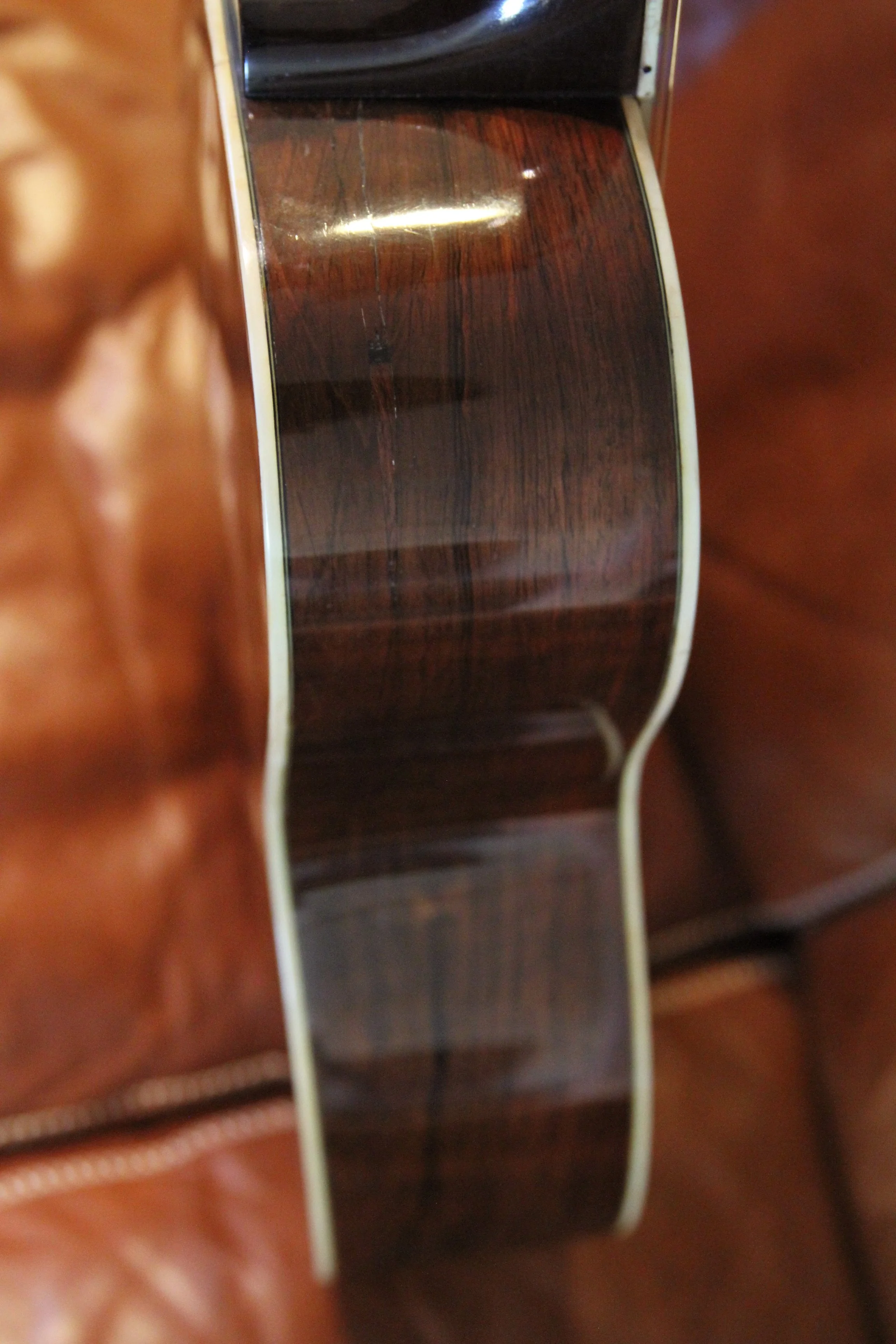 Close-up of a guitar's sound hole and strings, showing wood grain on the guitar body.