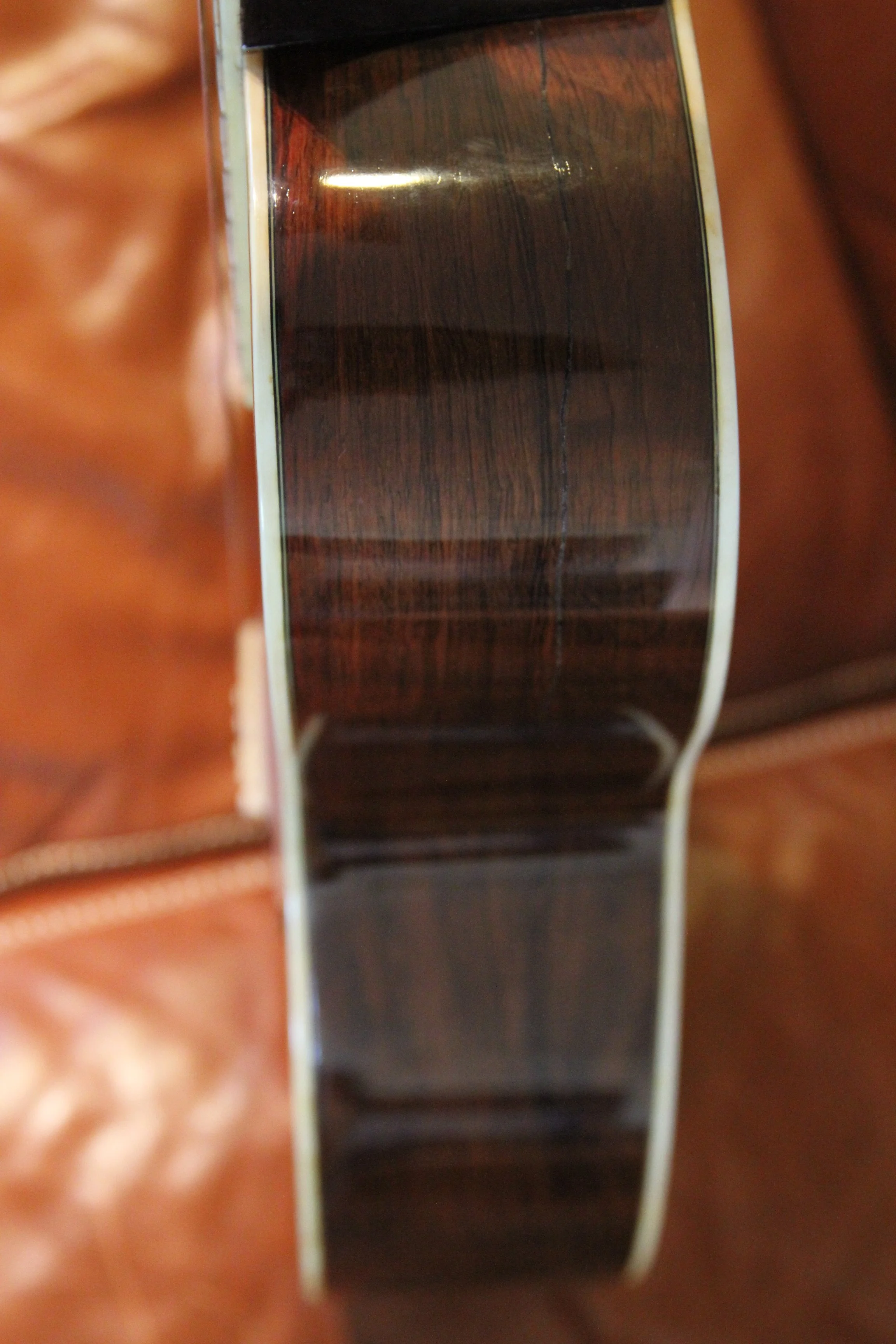 Close-up of a guitar fretboard showing the strings and wood grain.
