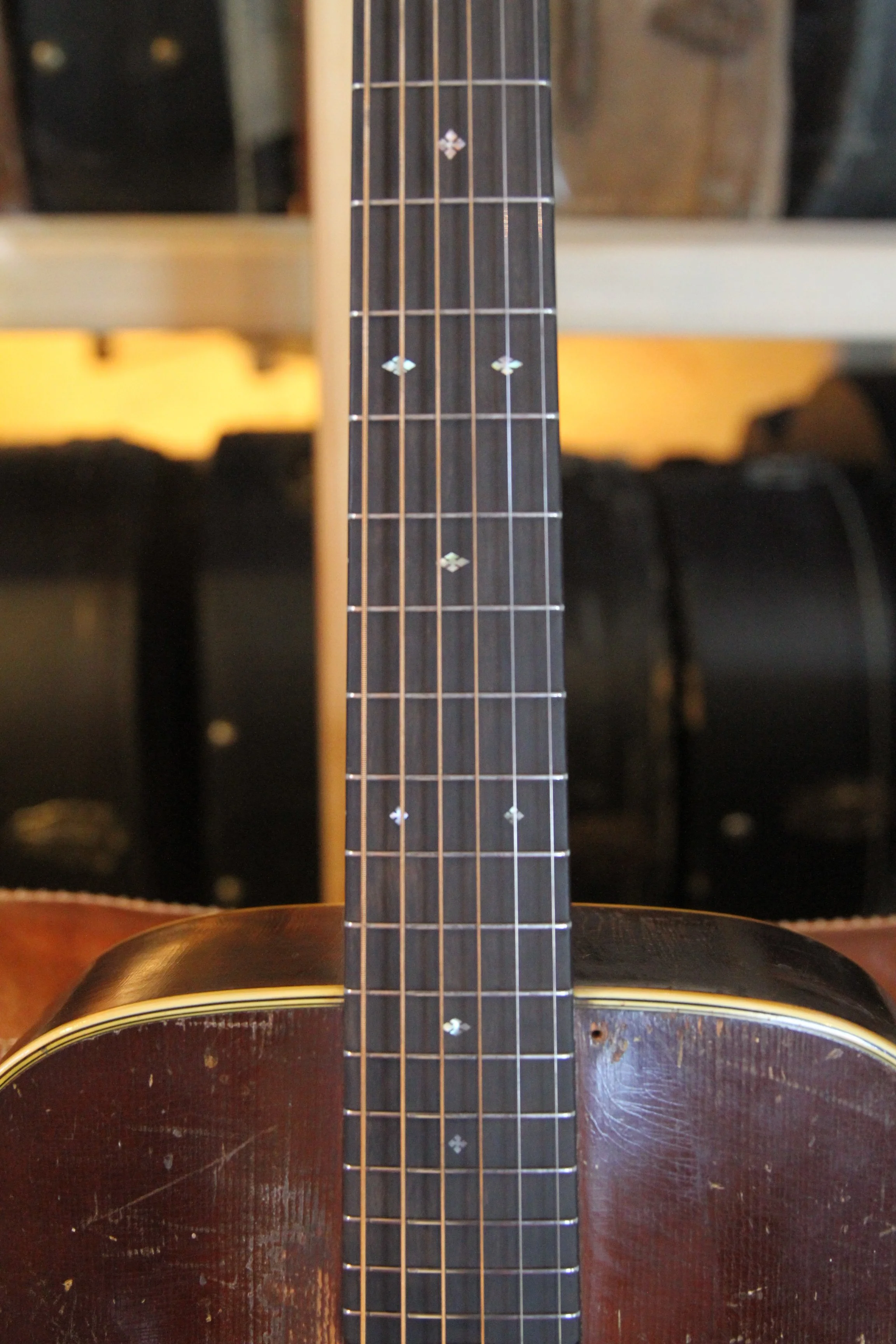 Close-up of a vintage Martin guitar's fretboard and body, with visible diamond and snowflake inlays.