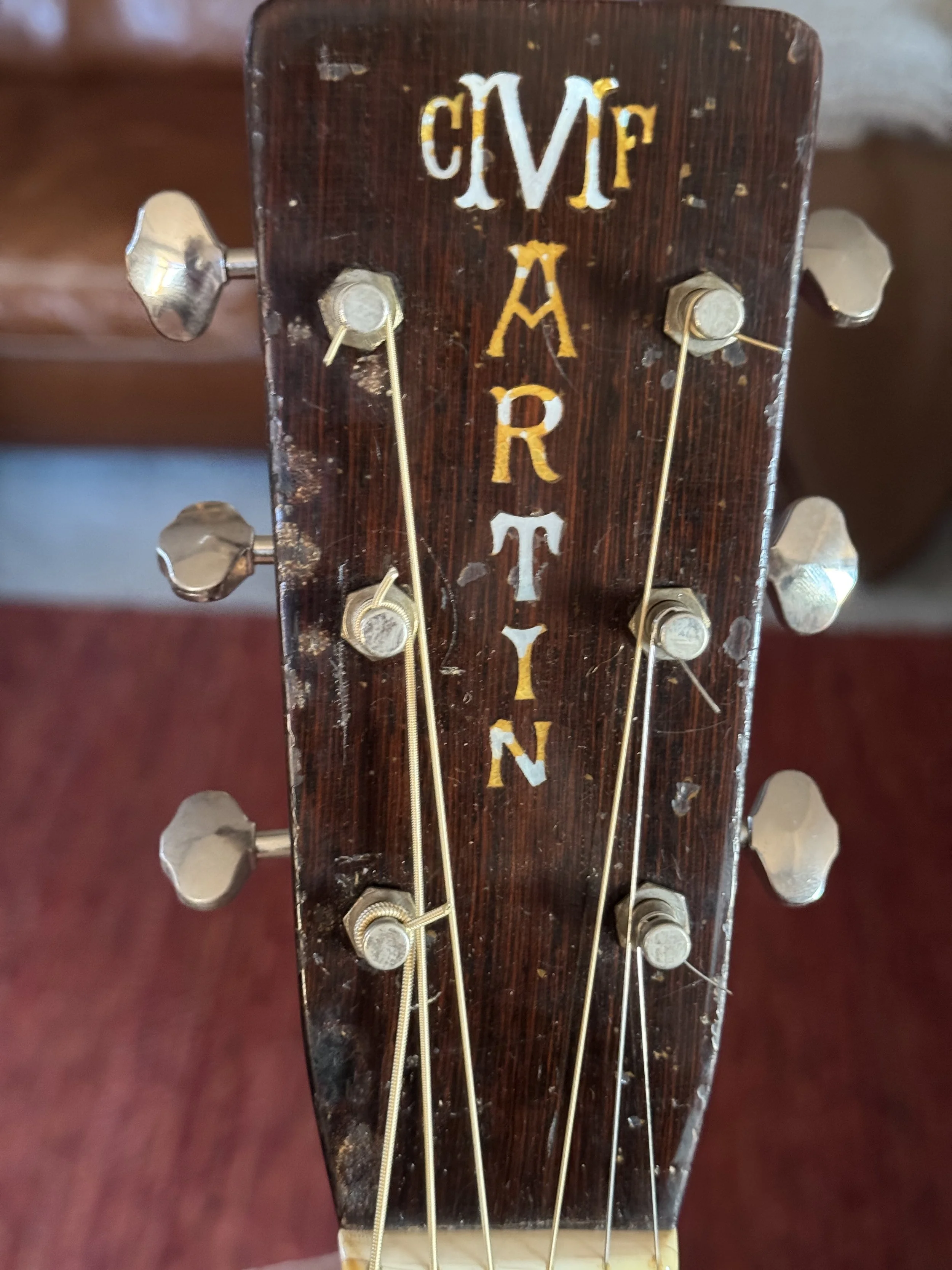 Close-up view of a Martin archtop guitar headstock with vintage tuning pegs .