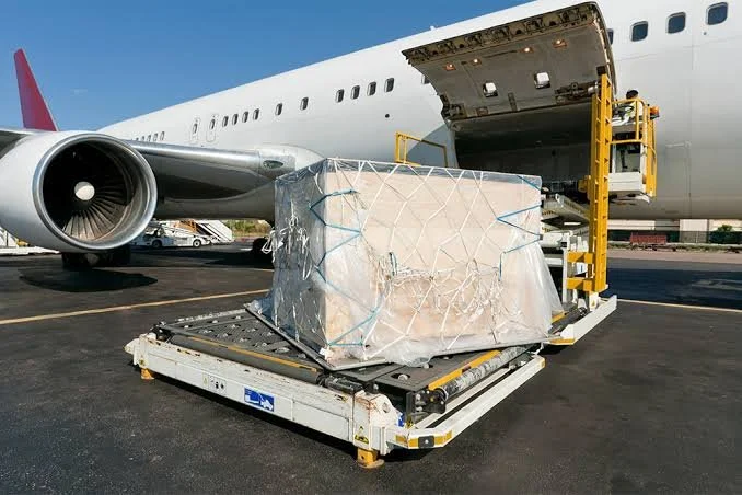 Cargando una caja grande envuelta en plástico en un avión de carga en un aeropuerto.