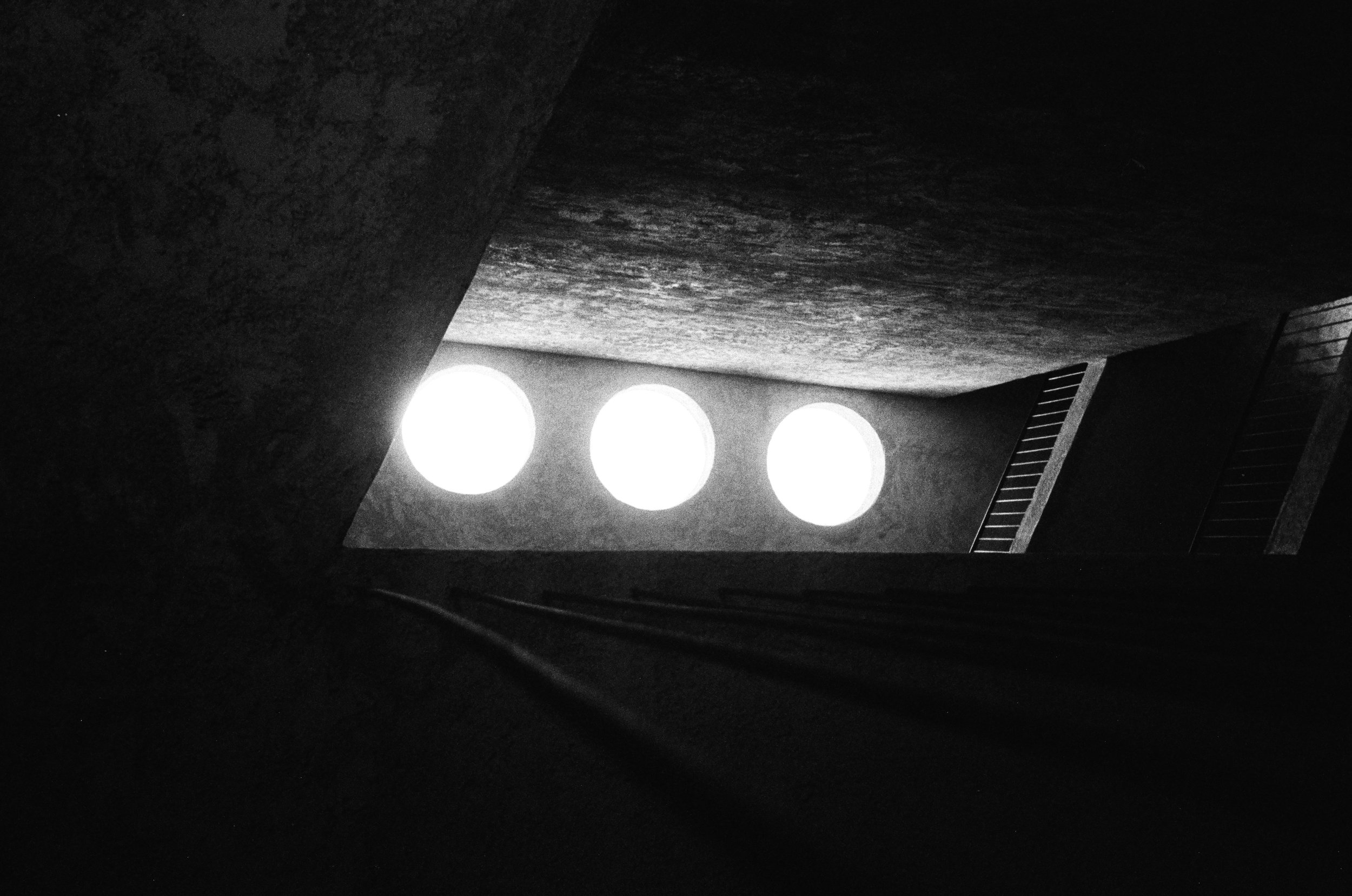 Quattro luci bianche luminose su una superficie scura con una ringhiera in metallo a destra.