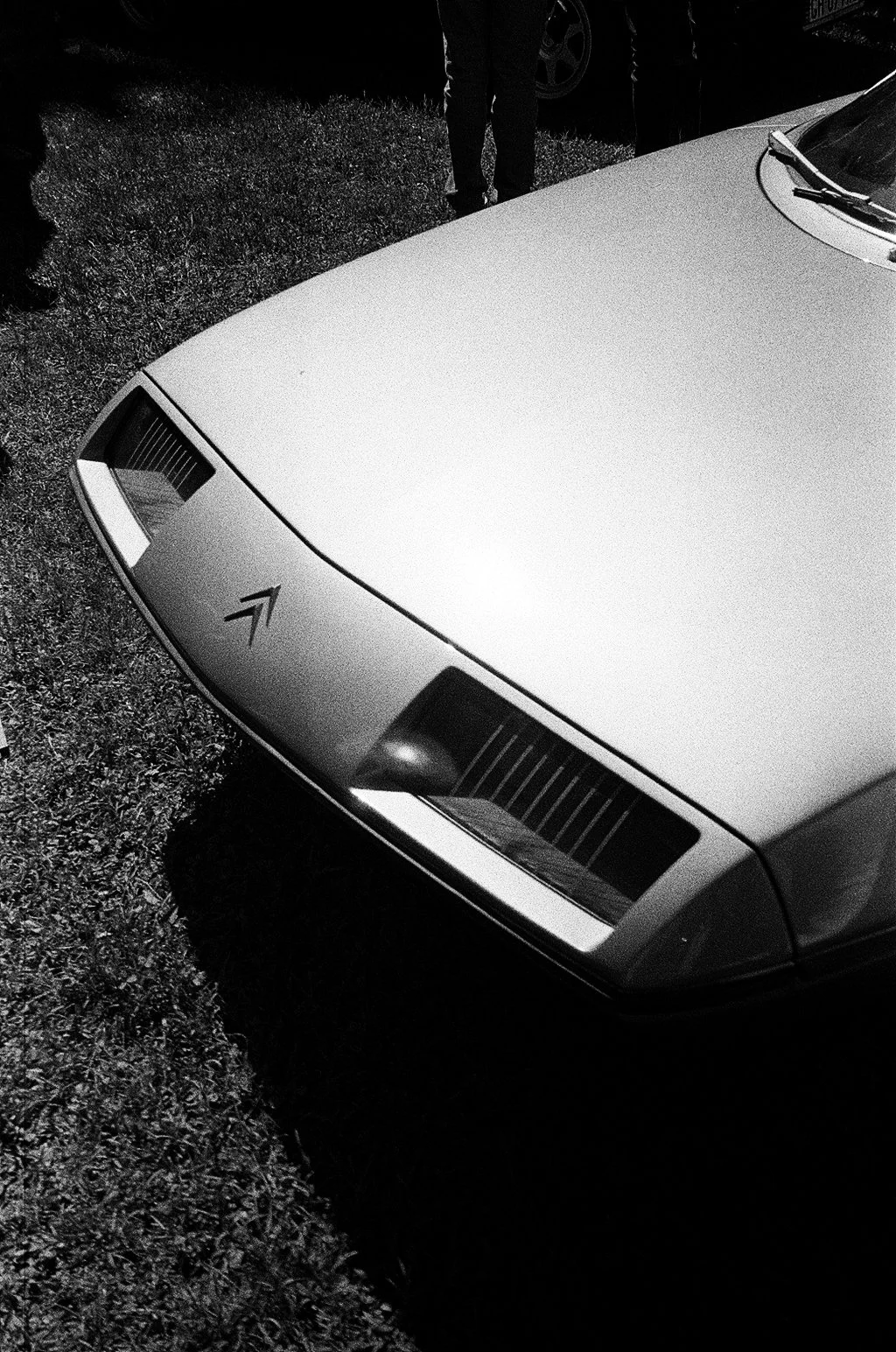 Fronte di un'auto d'epoca parcheggiata su un prato, vista dall'alto, in bianco e nero.