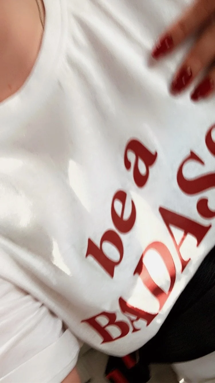 Close-up of woman in badass white tshirt with red lettering and a hand with red-painted nails