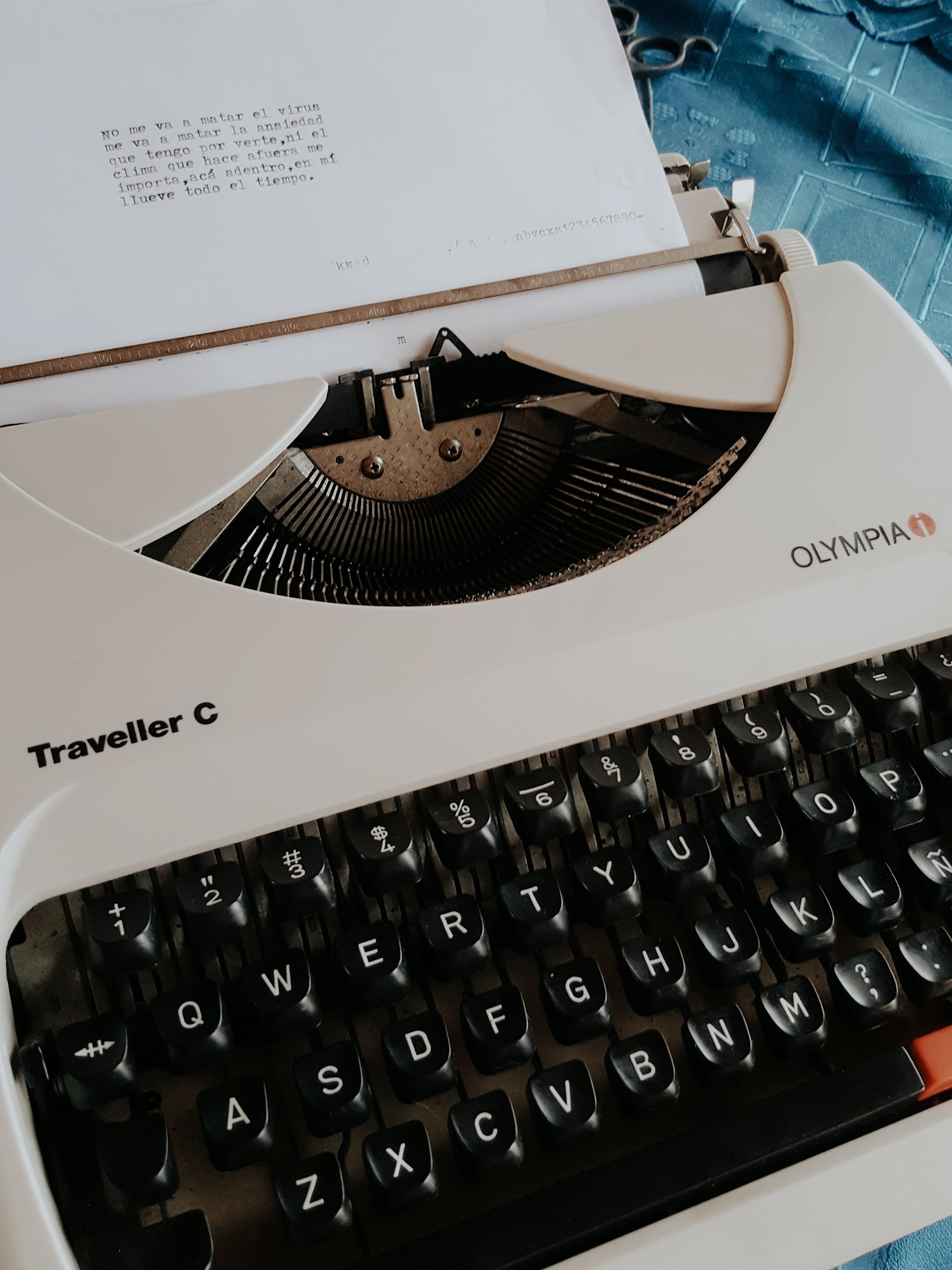 Close-up of an Olympia Traveller C manual typewriter typing Spanish text on white paper.