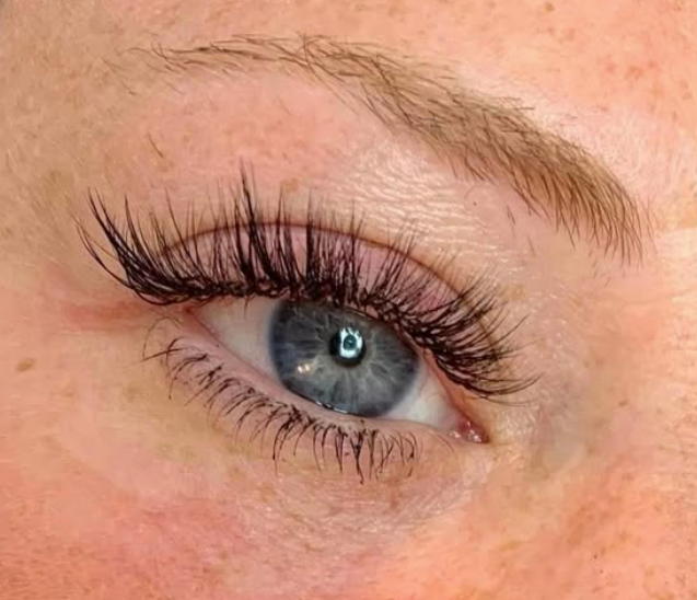 Close-up of a blue eye with long, thick eyelashes and well-groomed eyebrows.