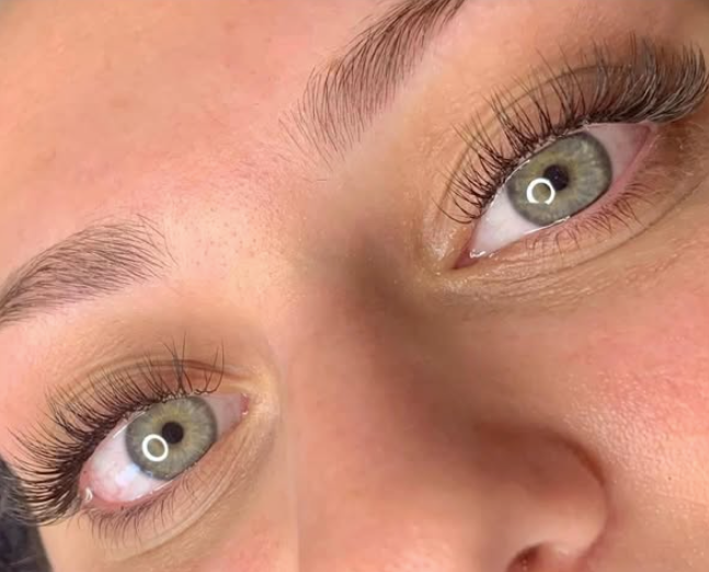 Close-up of a person's eyes with light-colored irises, long eyelashes, and well-groomed eyebrows.