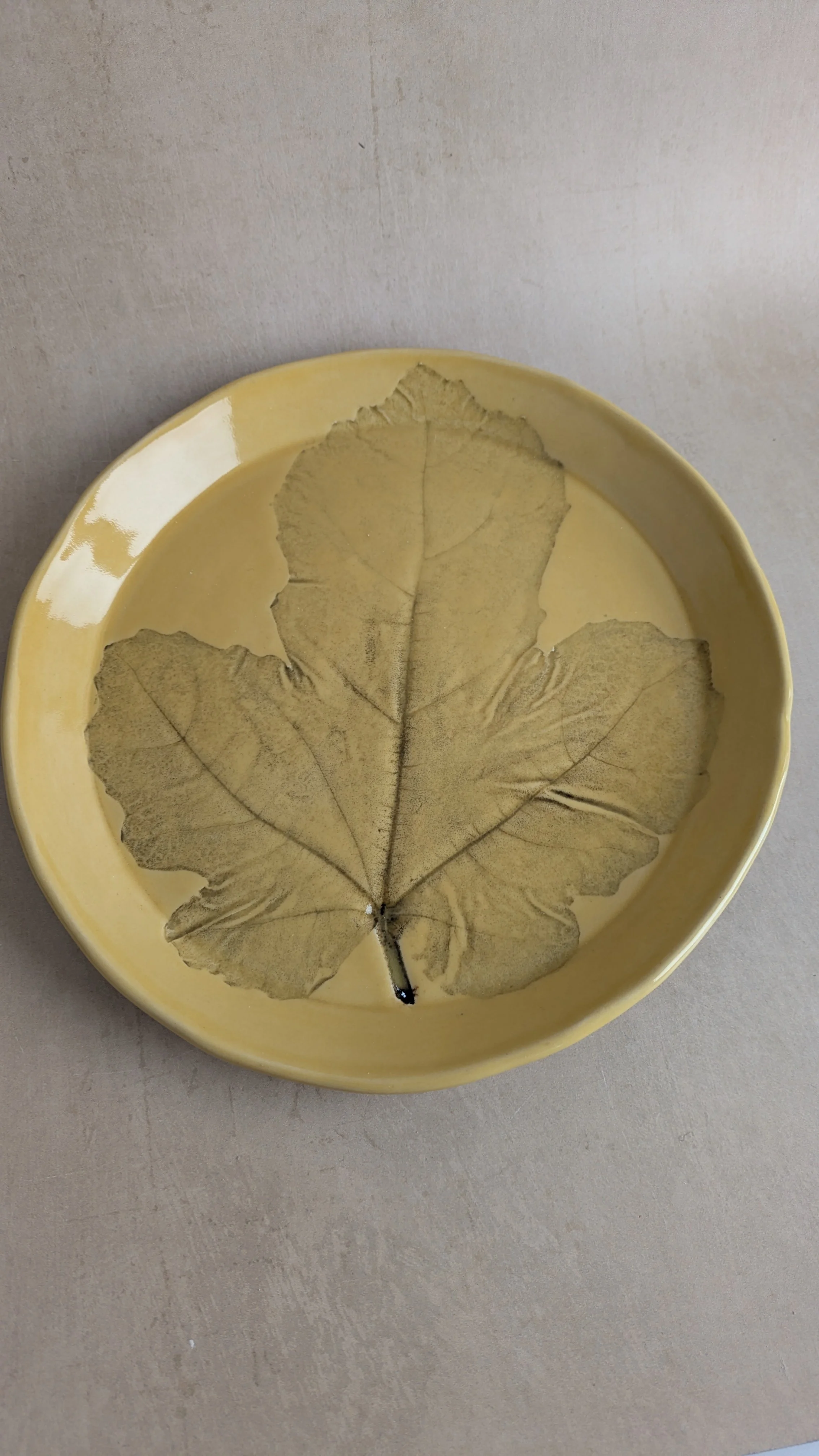 Handmade yellow‑glazed fig‑leaf plate, botanical imprint detail.