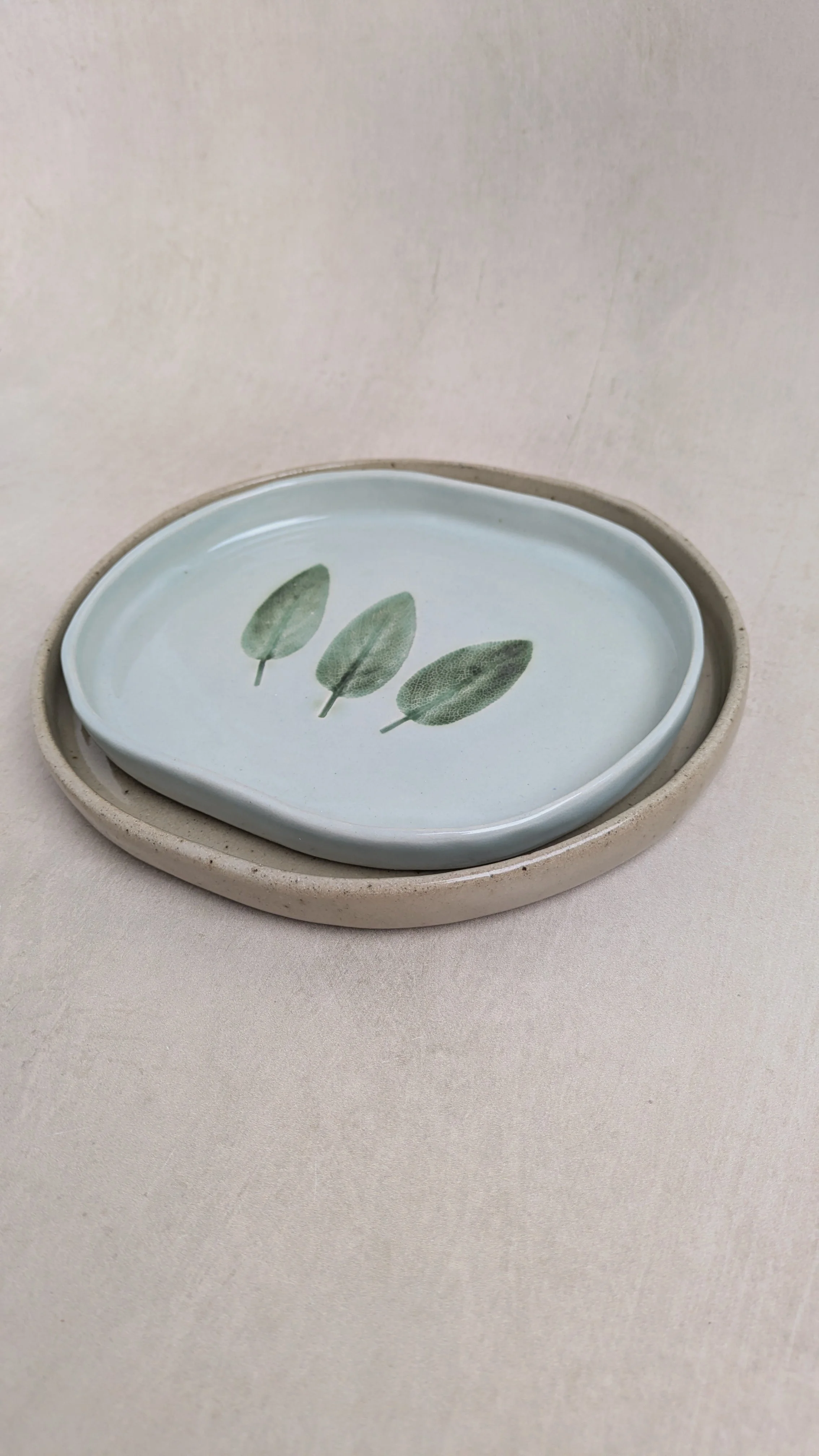 Handmade speckled stoneware plates with pressed sage leaf motif, crafted by Fireweed Pottery