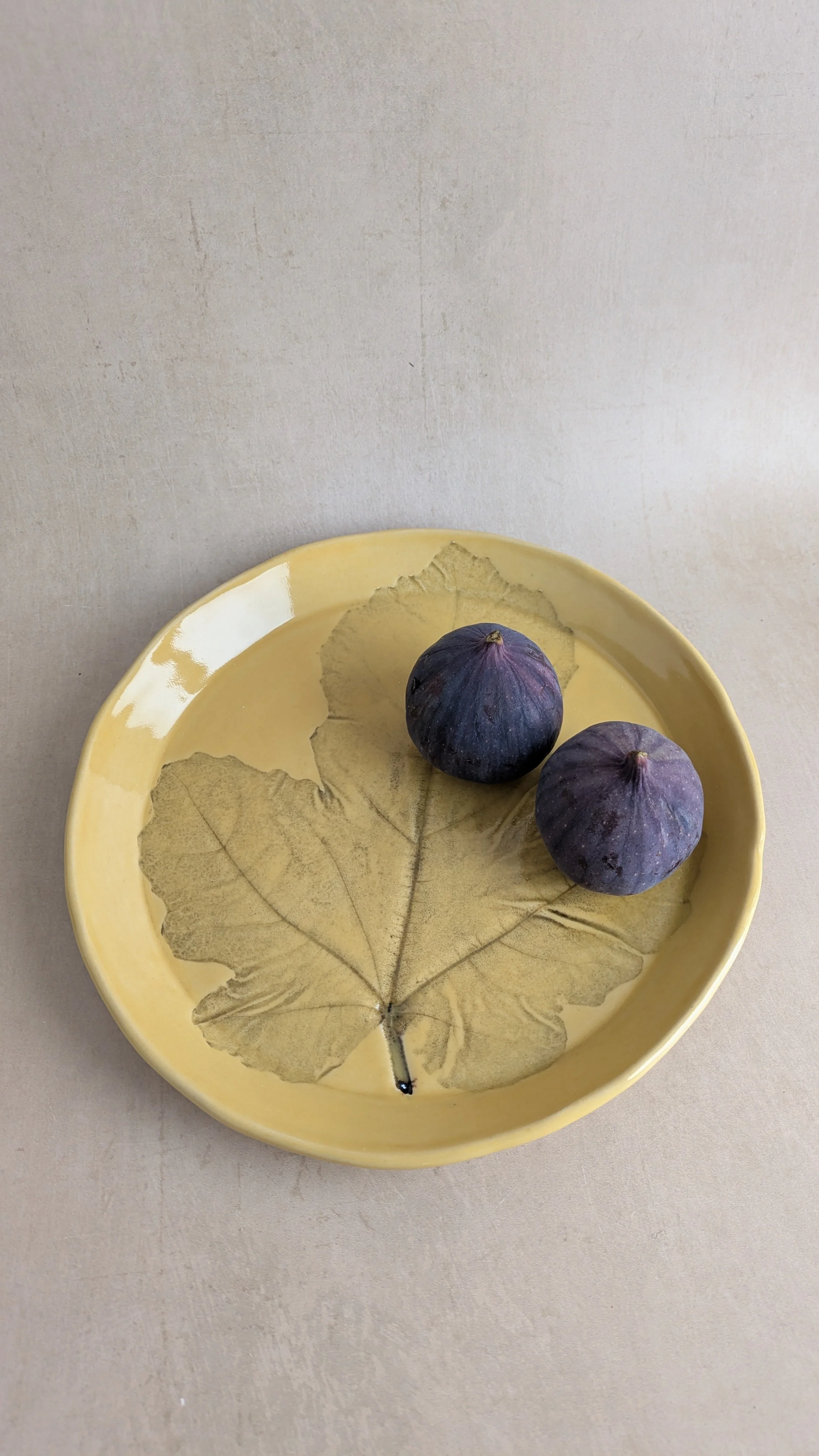 Ceramic fig‑leaf plate and mug set with two fresh figs, natural light styling.