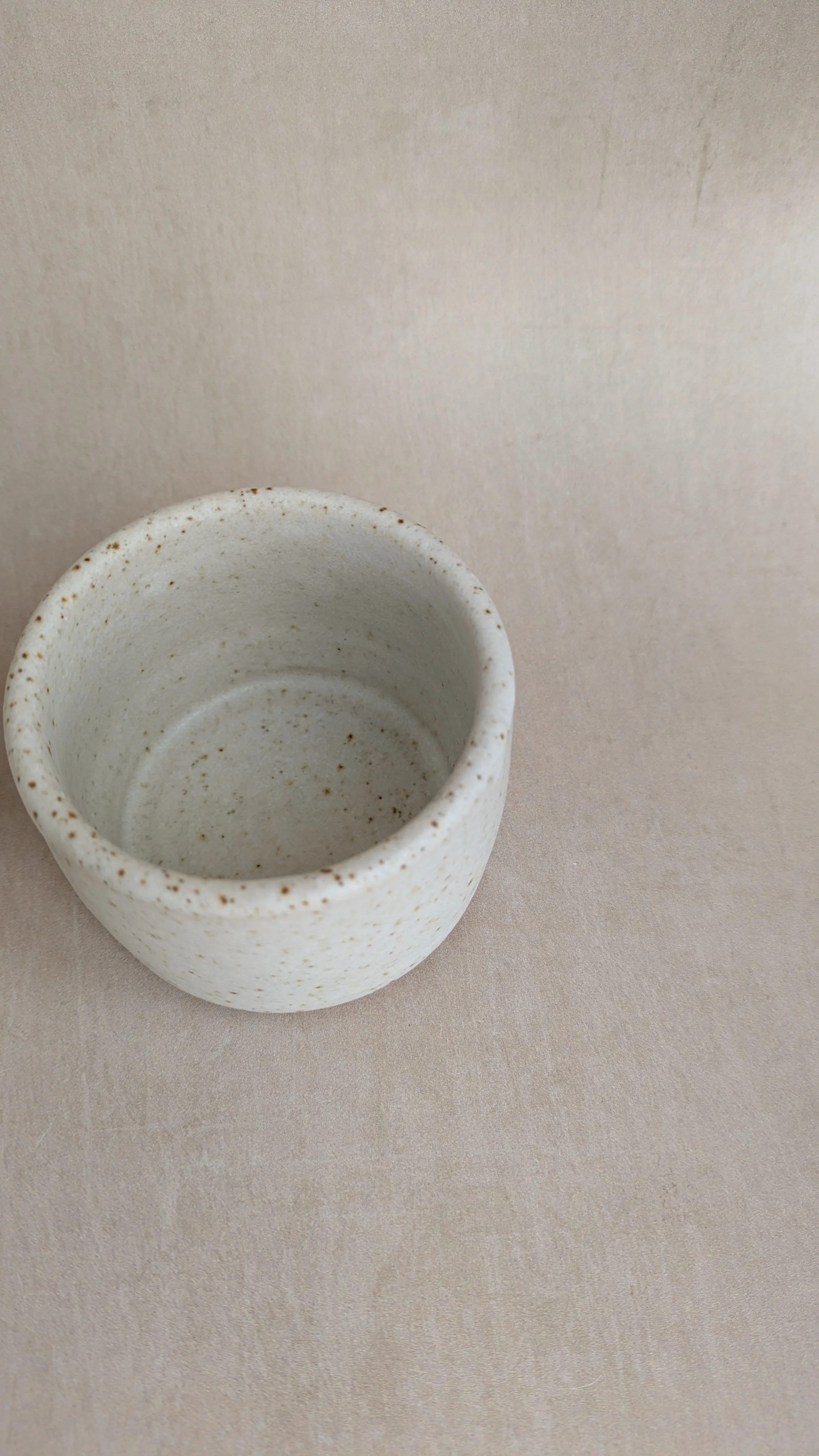 Top view of cream speckled pottery condiment pot showing interior glaze.