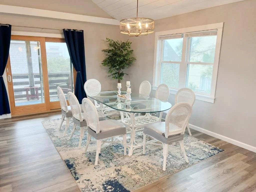 Dining room with sliders that lead to a screened porch with shades and seating for 4