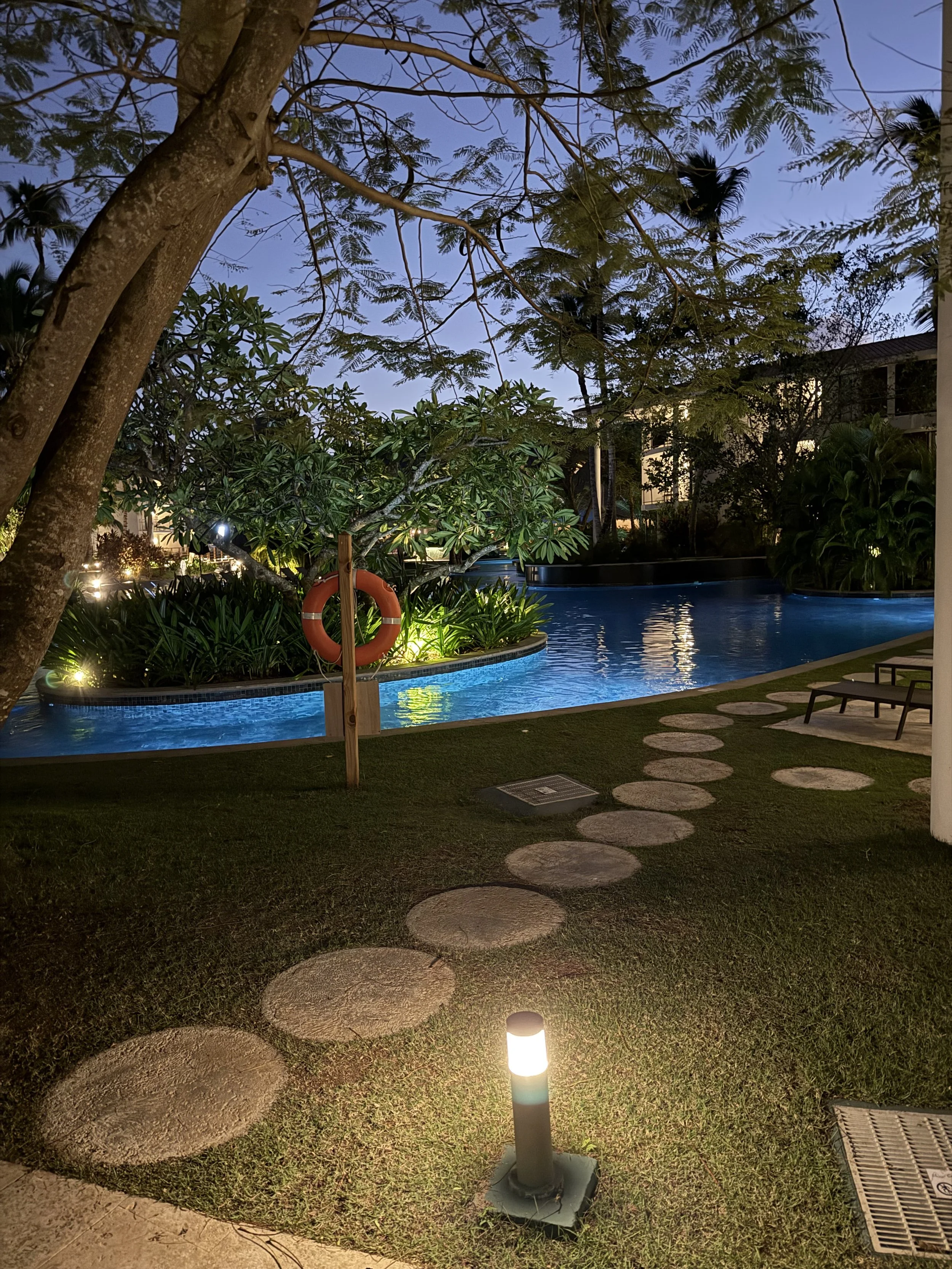 Peaceful evening view of a luxury resort with illuminated walkways and tropical landscaping.
