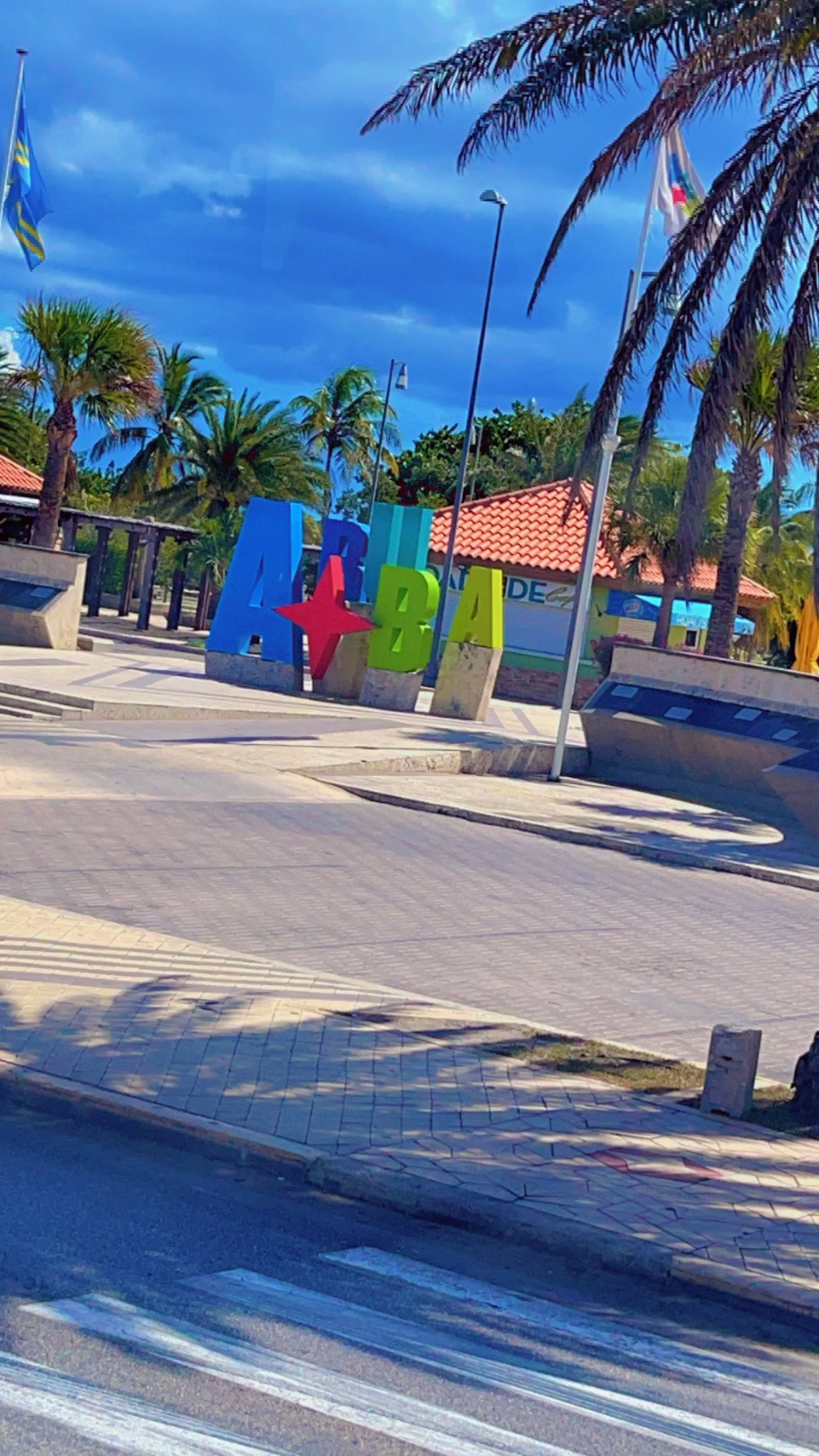 Beautiful tropical resort with palm trees and landscaped walkways around the Aruba sign.