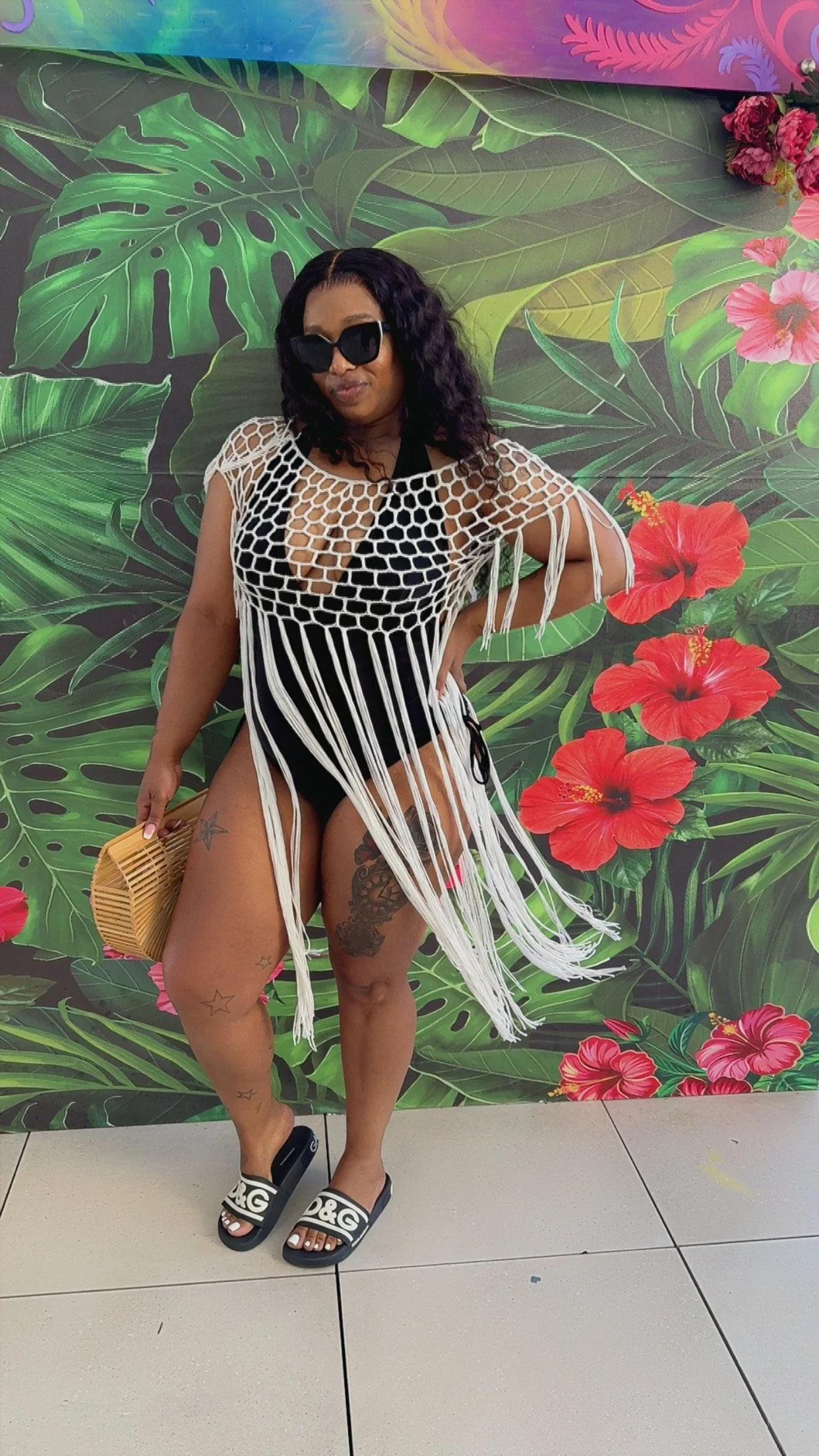 Erica posing in front of a colorful tropical mural while exploring a vacation destination.
