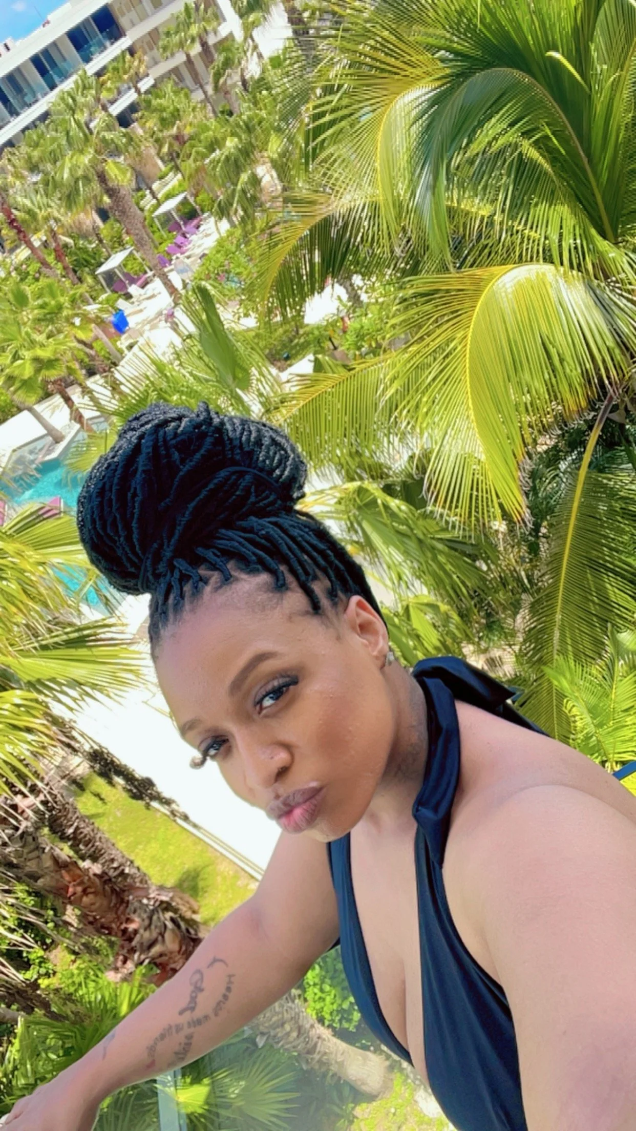 Erica relaxing beneath palm trees at a tropical resort during vacation.