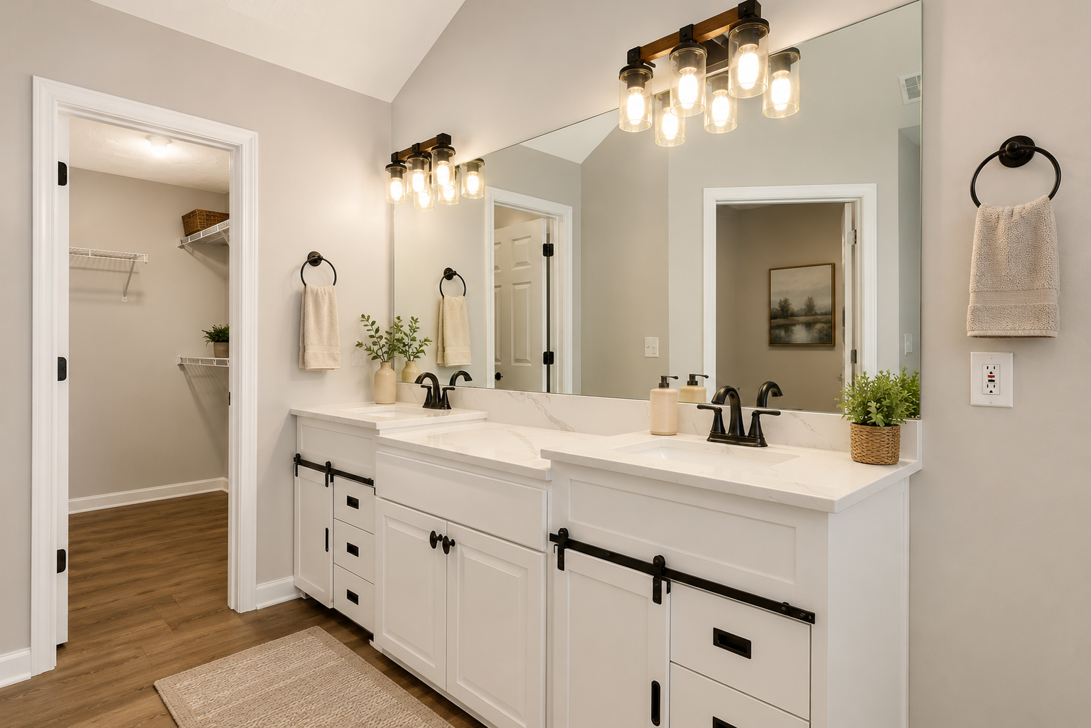 Modern bathroom with double sink vanity, large mirror, black fixtures, hanging lights, and neutral decor, including plants and towels, with a walk-in closet in the background. Completed by Sawdust.