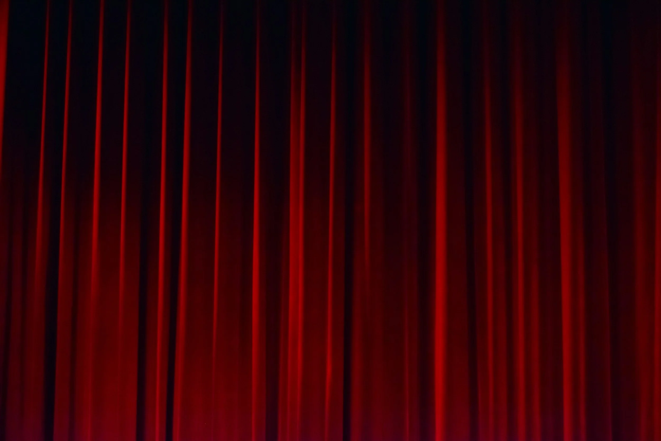 Red stage curtains with vertical pleats.