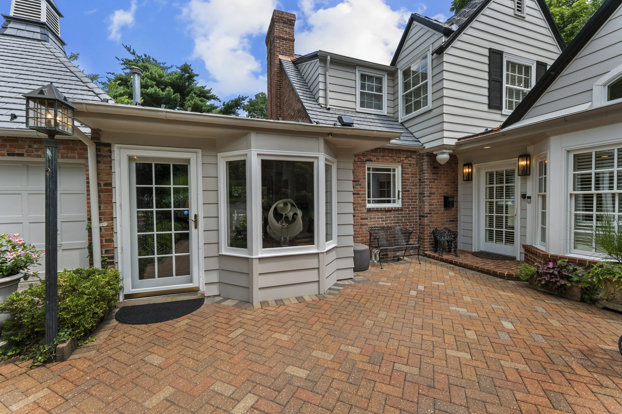 Rear exterior of 17 Devon Road featuring brick patios, outdoor entertaining areas, and mature landscaping.