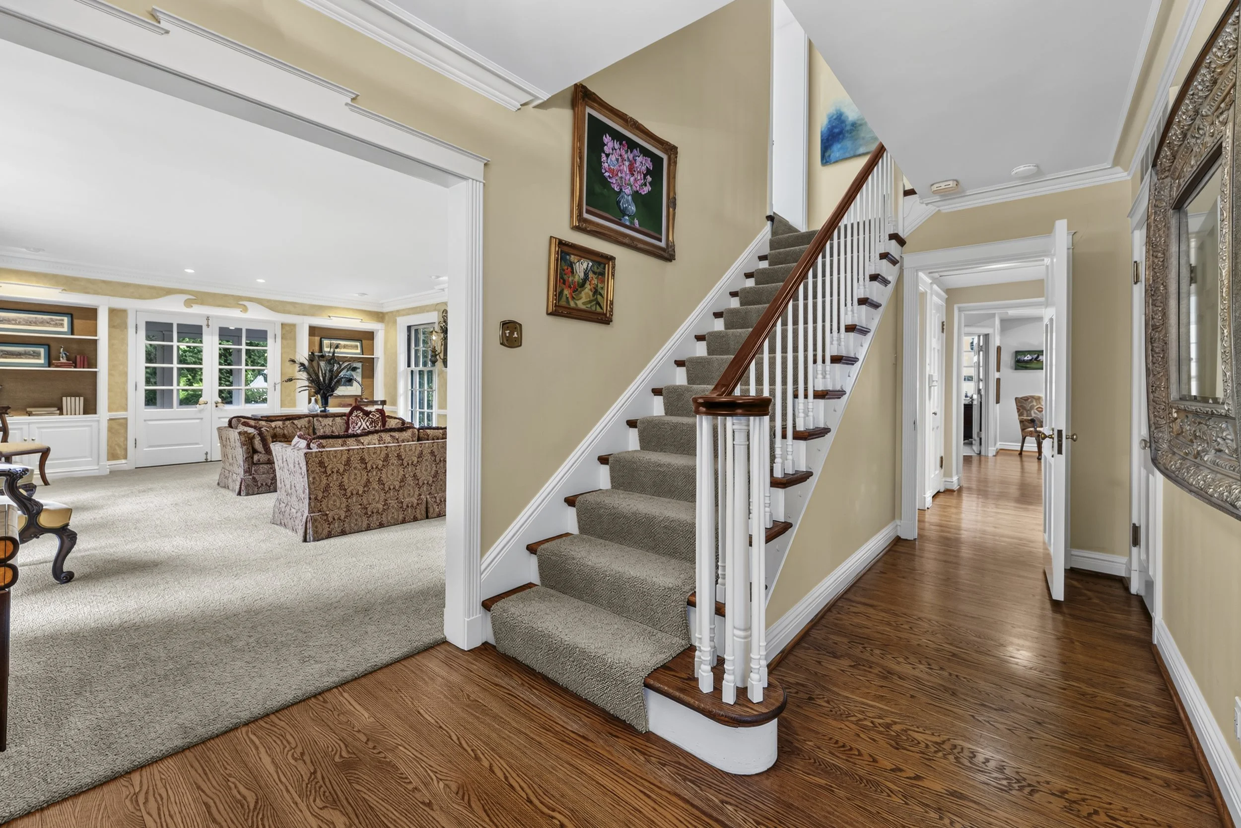 Welcoming entry hall with hardwood floors, staircase, and views into the main living spaces.