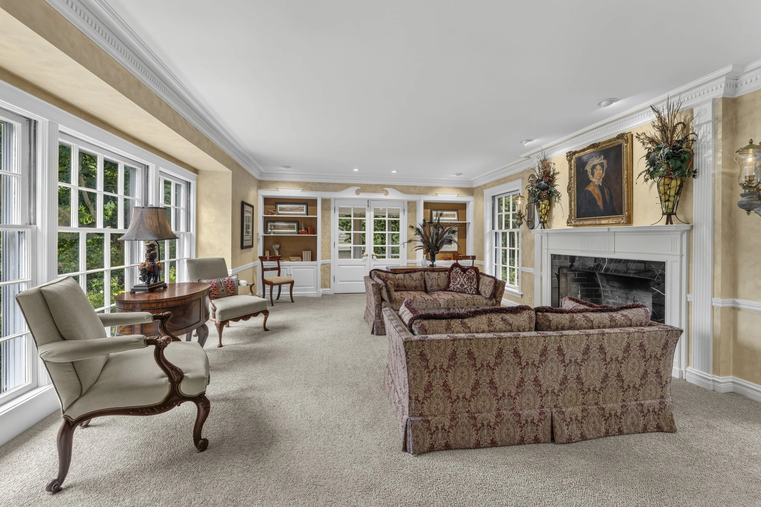 Formal living room with fireplace, oversized windows, and abundant natural light.
