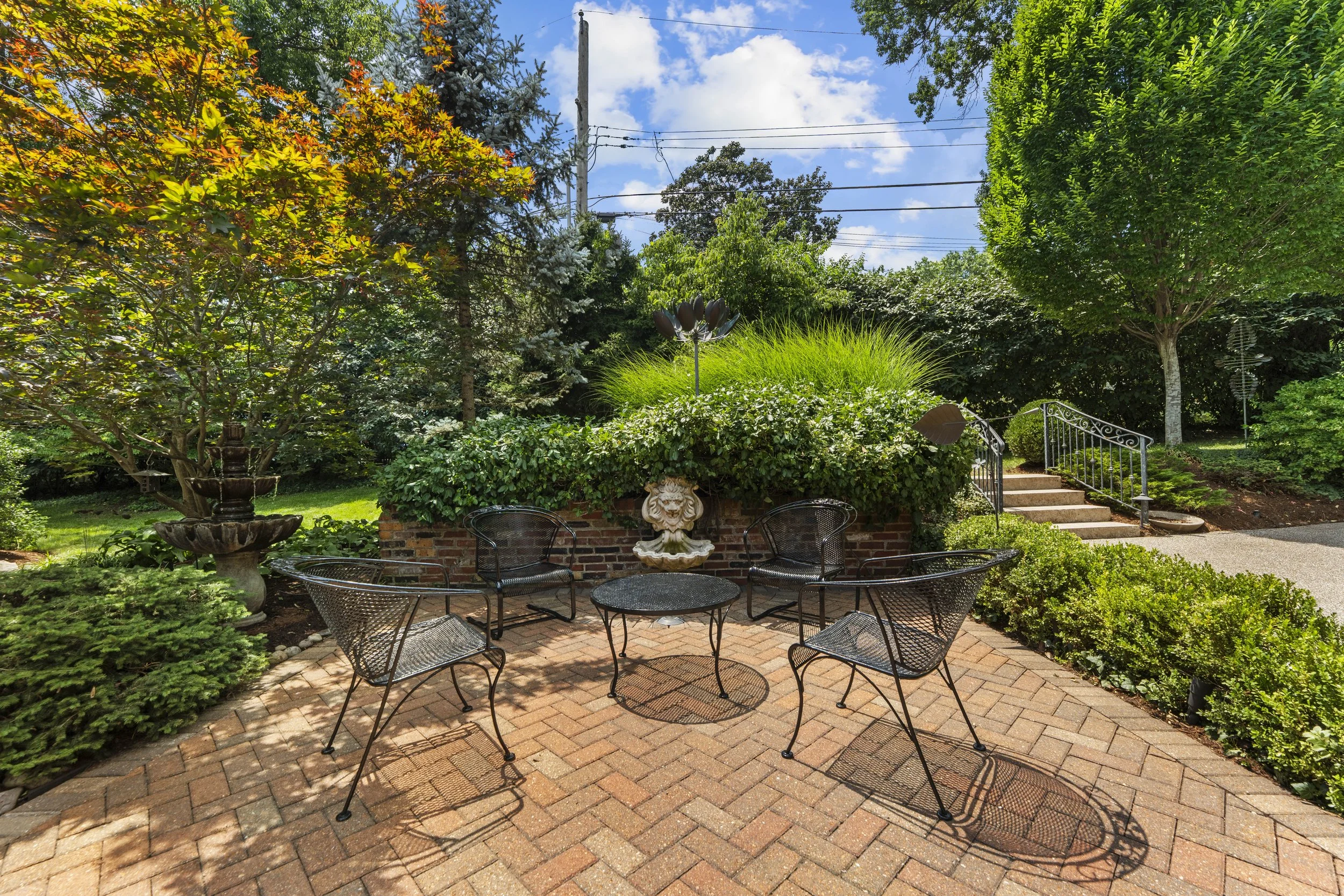 Brick garden patio with outdoor dining space, decorative fountain, and landscaped walkways.