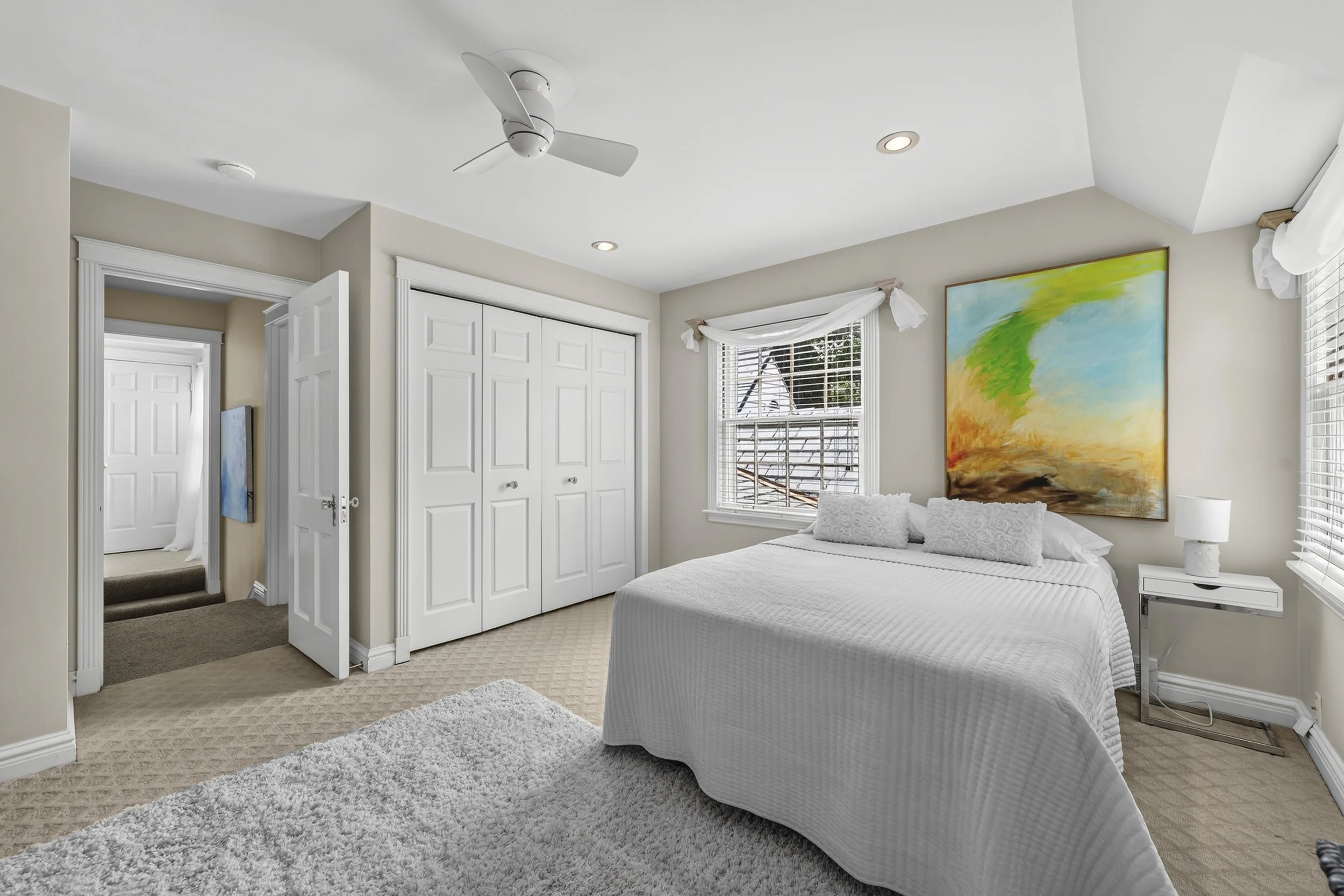 Bright bedroom with generous windows and peaceful views of the landscaped property.