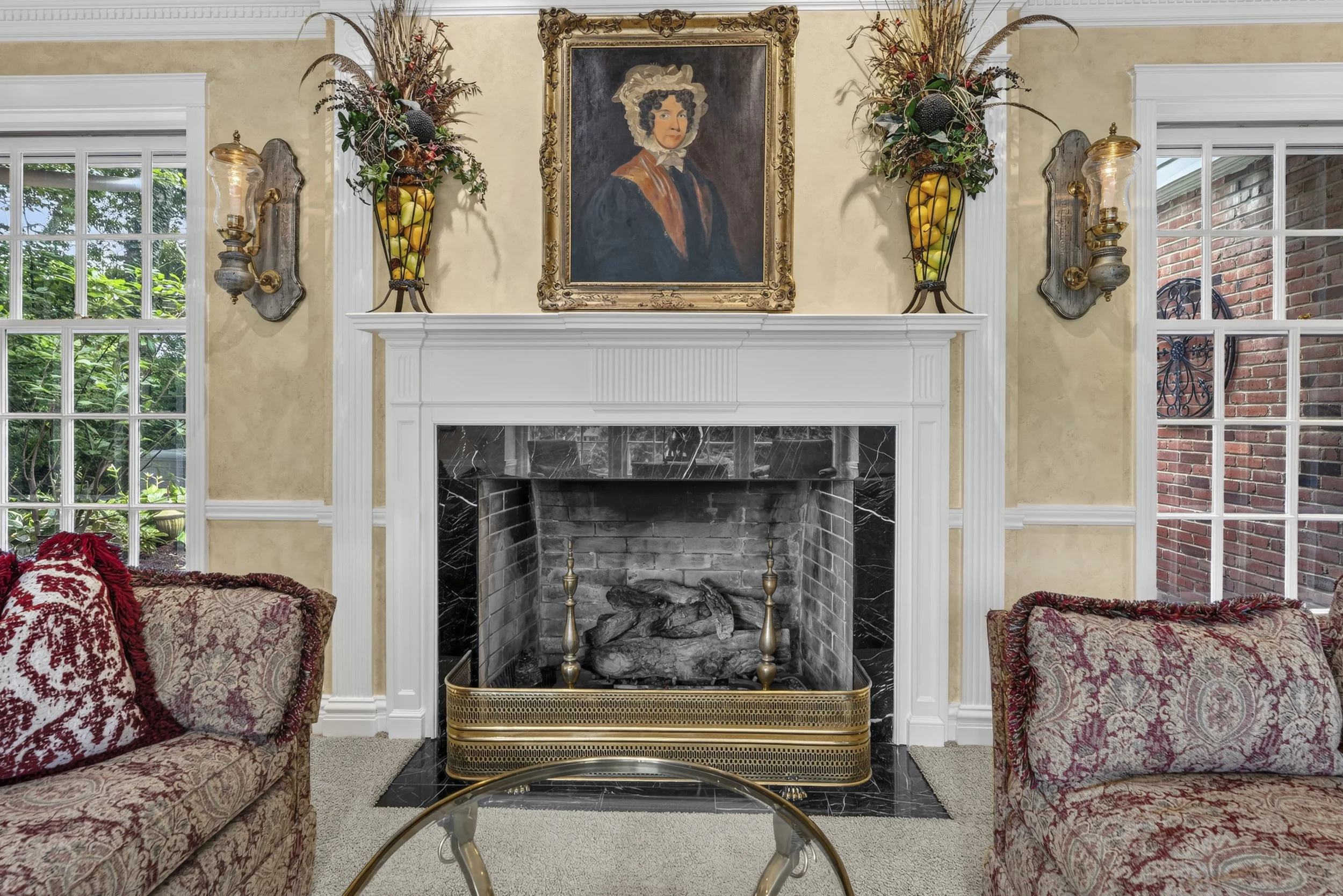 Formal living room with wood-burning fireplace, decorative mantel, portrait artwork, and windows overlooking the landscaped grounds at 17 Devon Road in Glendale, Missouri.