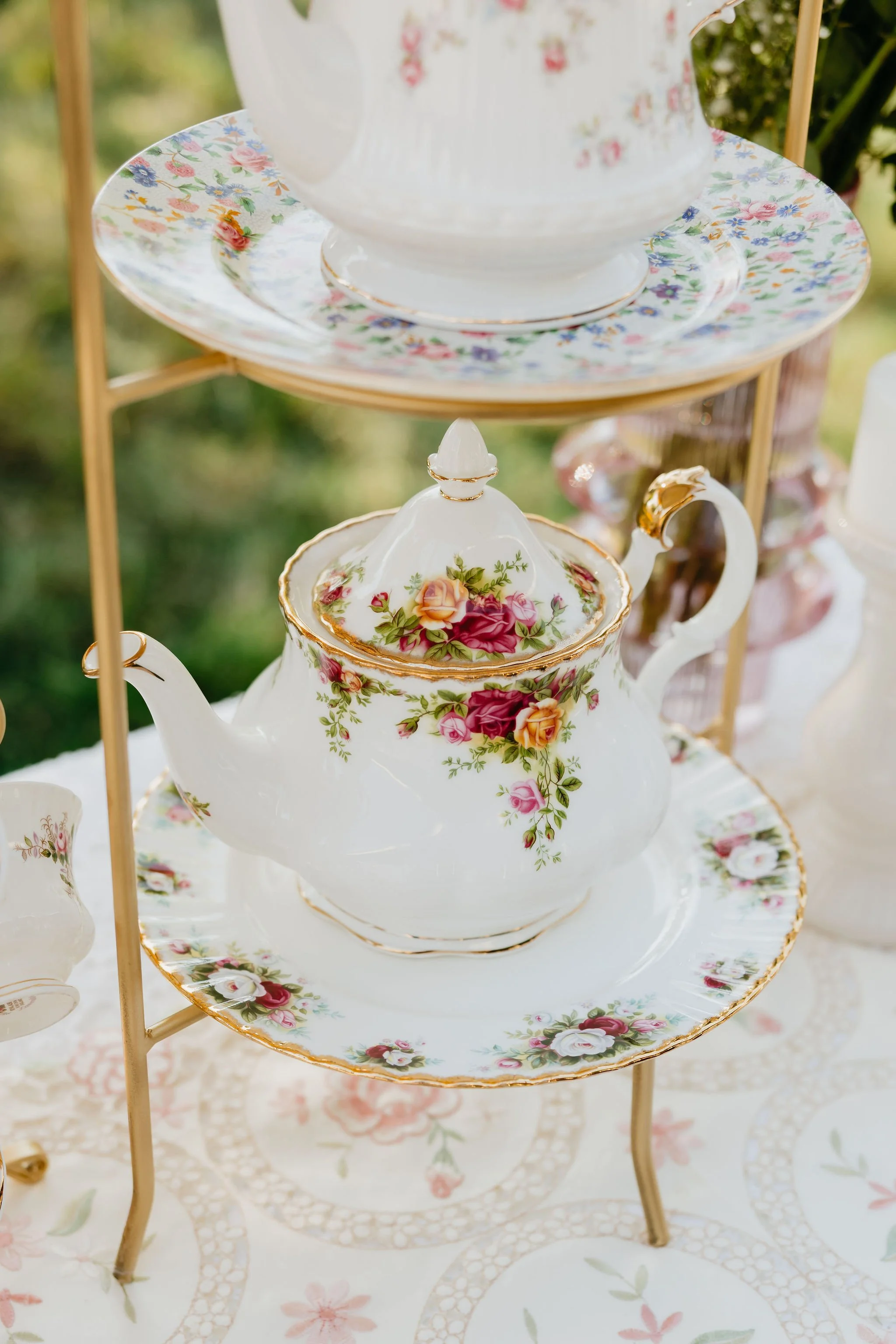 Close-up of vintage teapot with floral pattern on a decorative tiered serving stand.