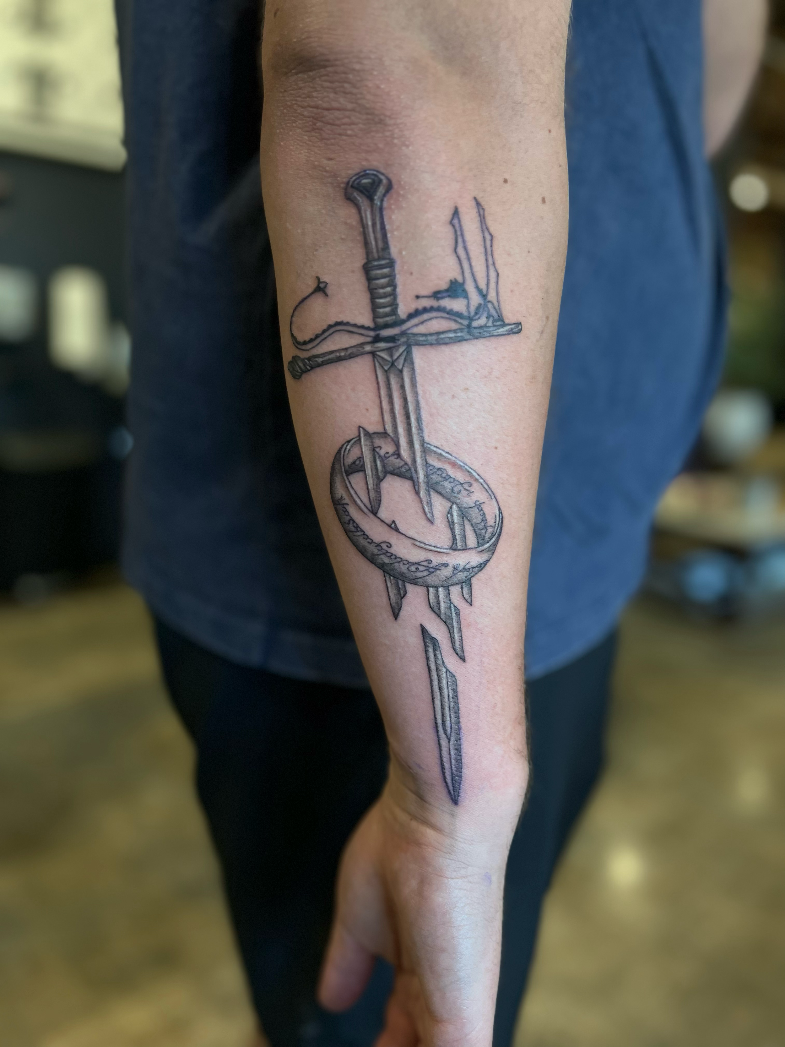 lord of the rings sword tattoo with fineline elven script and dotwork shading