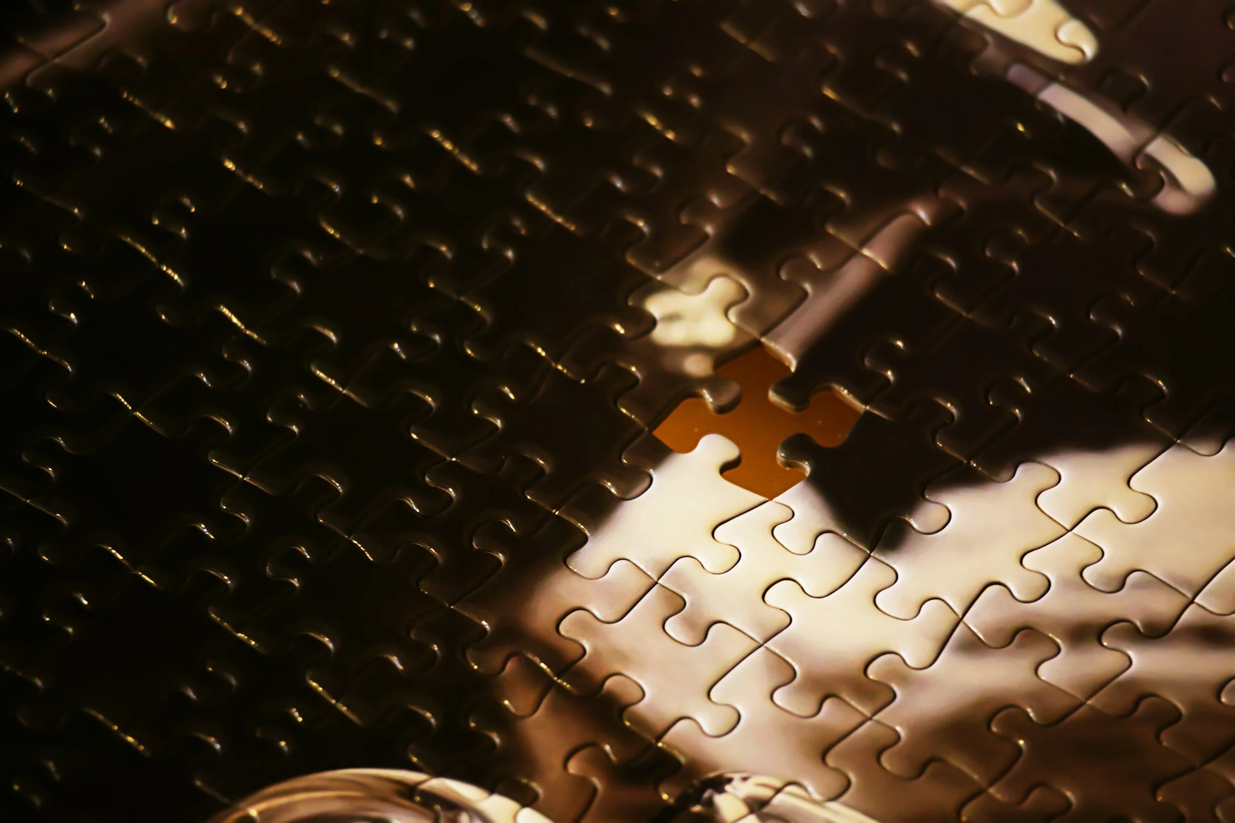 Close-up of a metallic jigsaw puzzle with a metallic and reflective surface, some pieces are connected while others are lying loose.