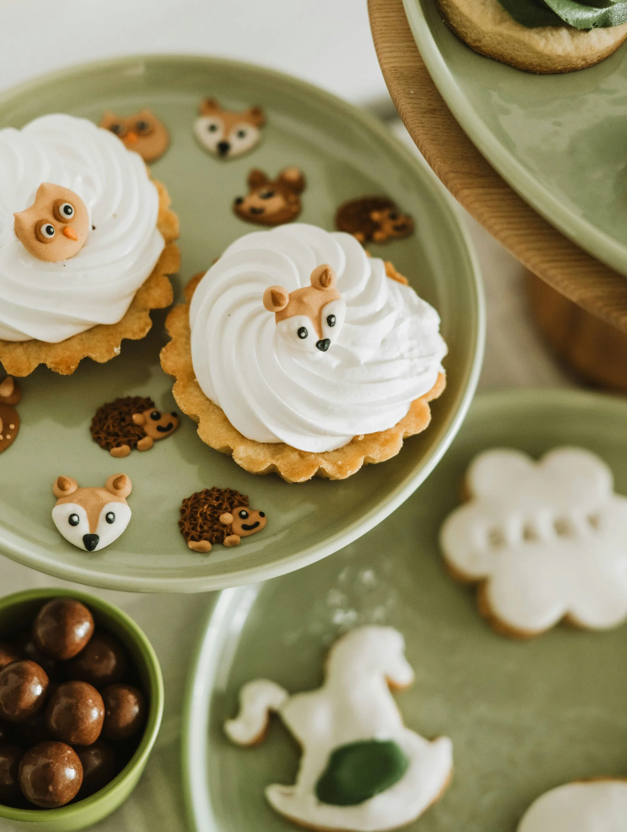 Decorated cookies with animal faces on green trays at a baby shower.
