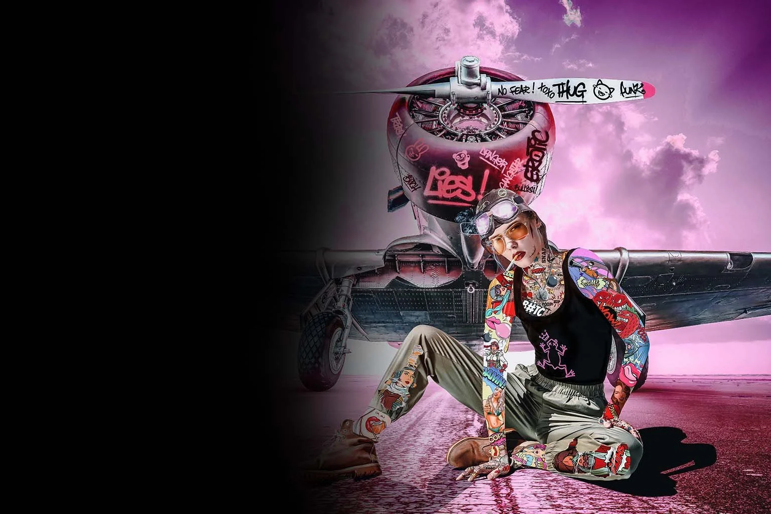 A person with tattoos and colorful clothing is sitting on the ground in front of a jet aircraft, with a pink sky and clouds in the background. The person is wearing large goggles, sunglasses, and has an edgy, punk style. The aircraft has graffiti and stickers on its surface, and the scene has a surreal, artistic vibe.