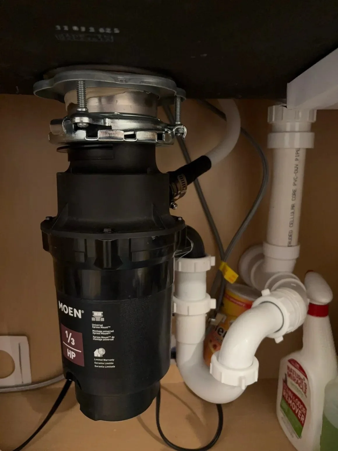 Moen garbage disposal and drain piping installed beneath a kitchen sink in Pensacola, Florida